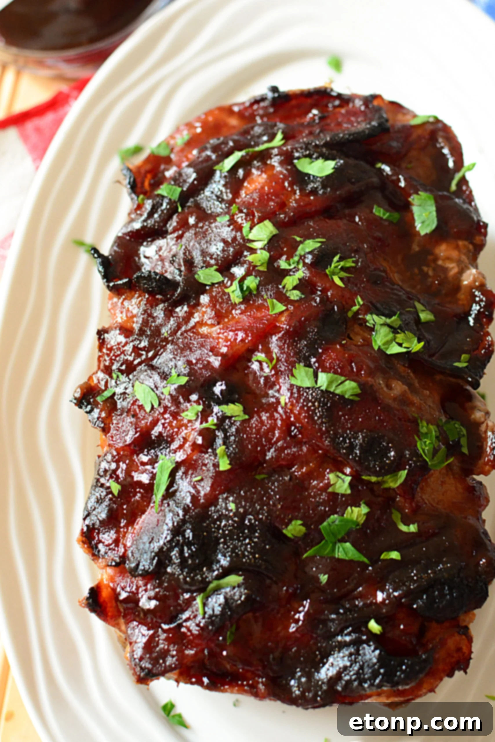 Caramelized Bacon Meatloaf 4 A perfectly sliced piece of candied bacon wrapped meatloaf on a plate, showing its juicy interior.