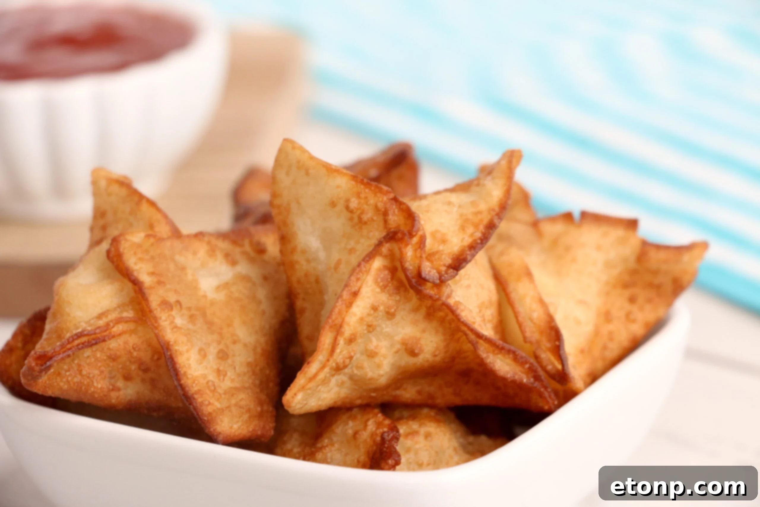 Crispy Cream Cheese Crab Bites 3 Close-up of golden brown crab rangoons on a cooling rack