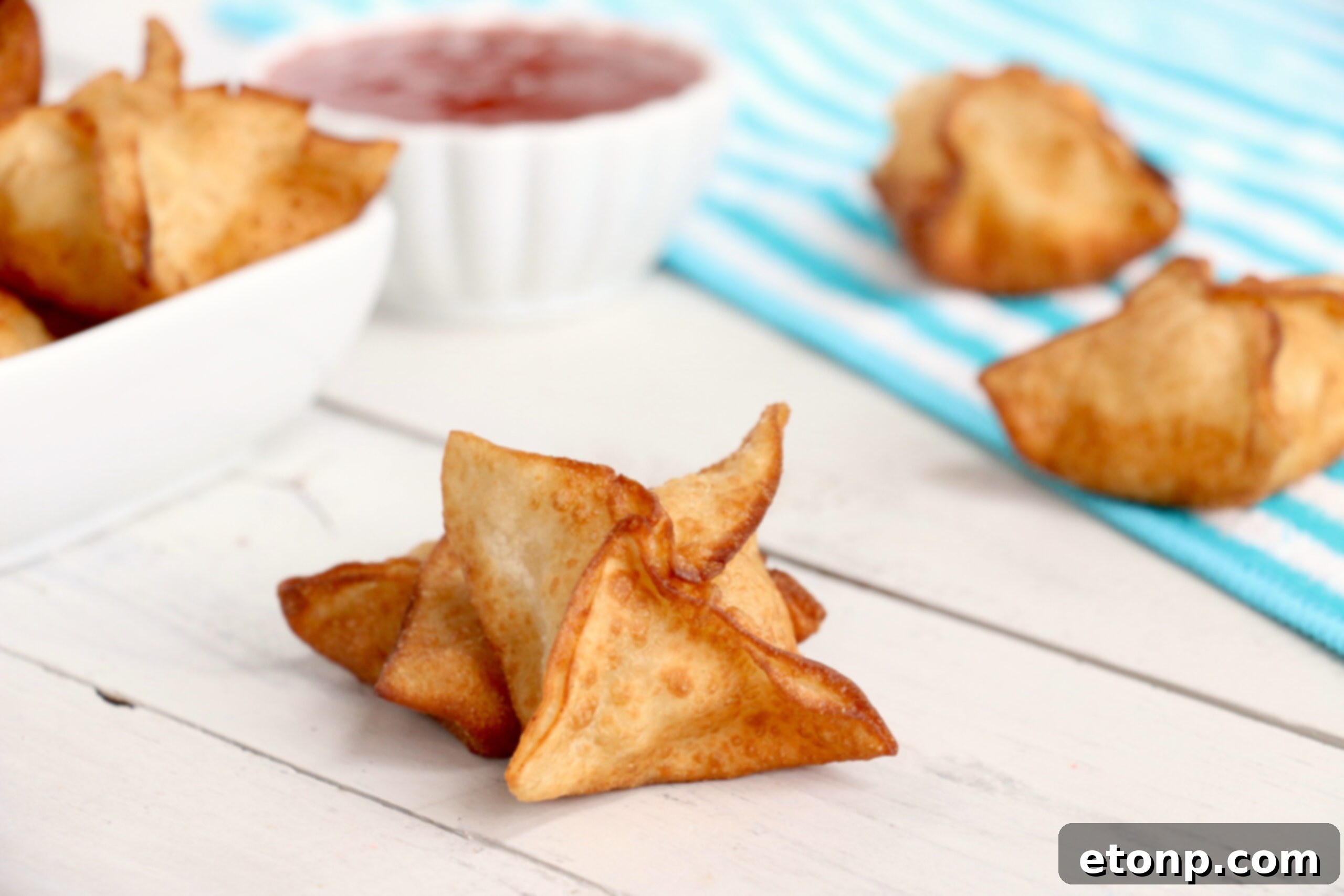 Crispy Cream Cheese Crab Bites 5 Homemade crab rangoons arranged on a wooden board with dipping sauce