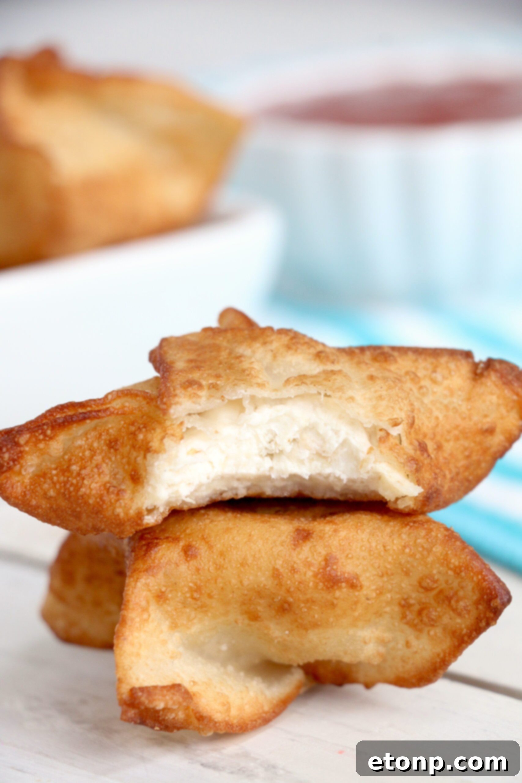 Crispy Cream Cheese Crab Bites 7 A basket full of golden, fried crab rangoons, ready to eat