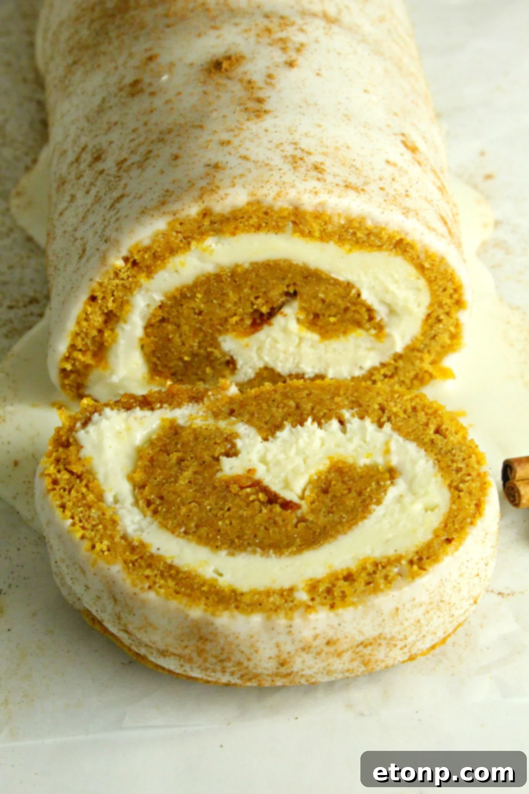 Another view of the pumpkin cake roll, showing a clean slice and the inviting swirl of cake and frosting.