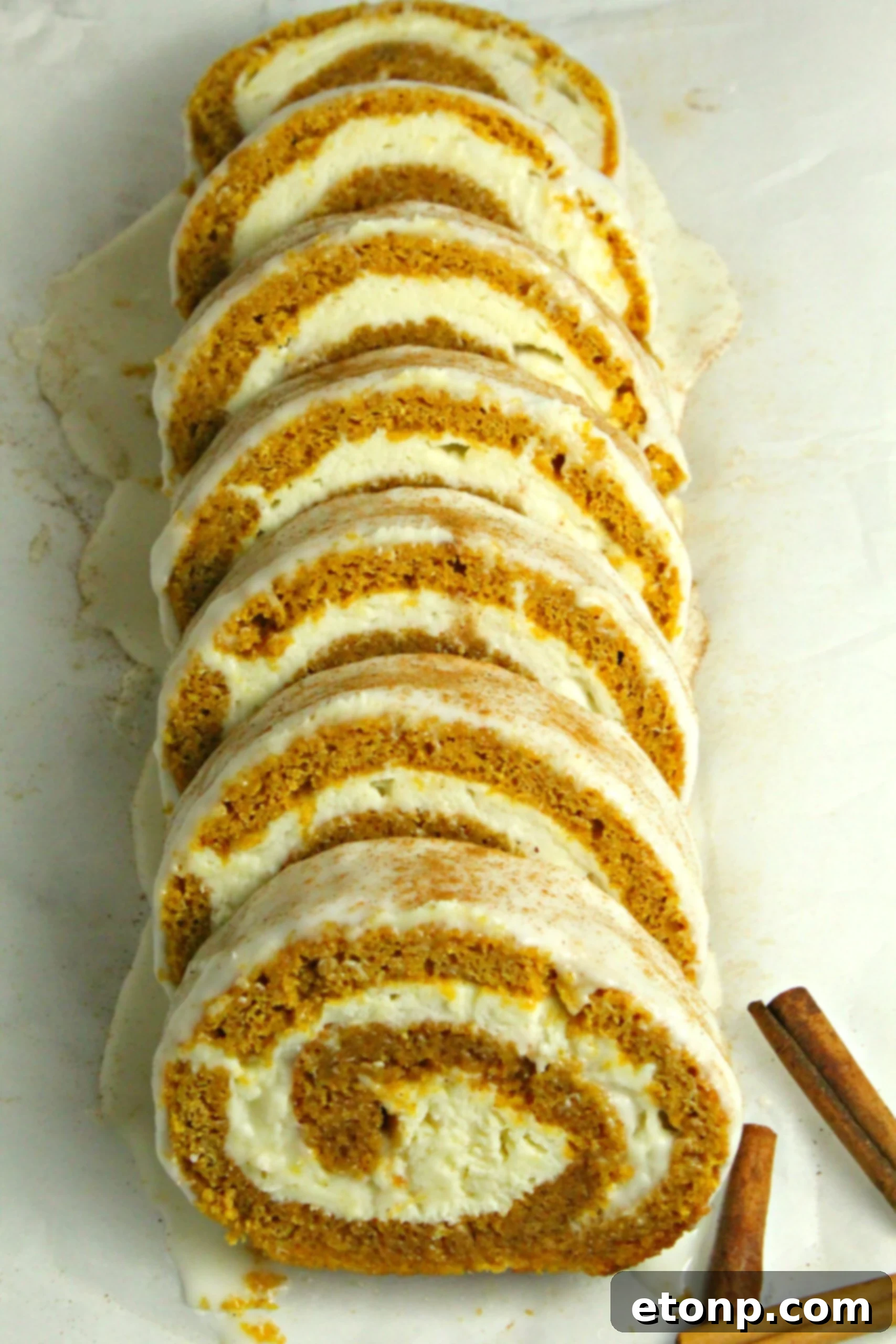 Two slices of pumpkin cake roll on a white plate, ready to be enjoyed with a cup of coffee.
