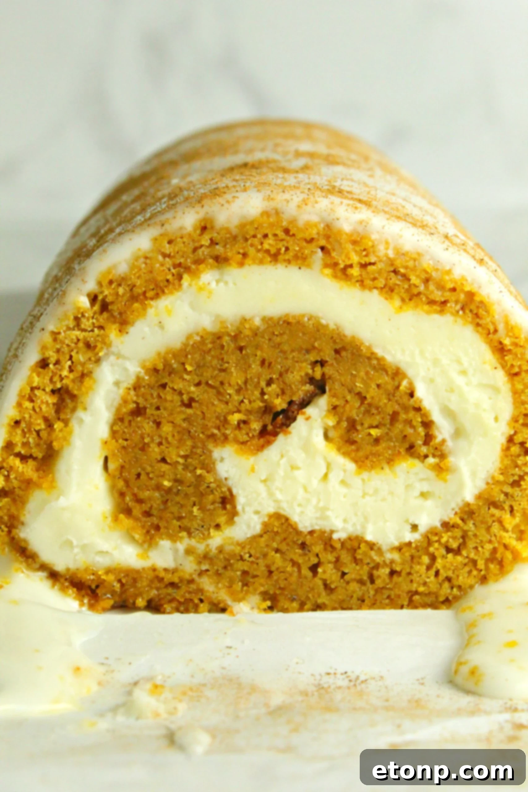 A final close-up of the pumpkin roll, ready to be sliced, showing the smooth exterior and a hint of the inner swirl.