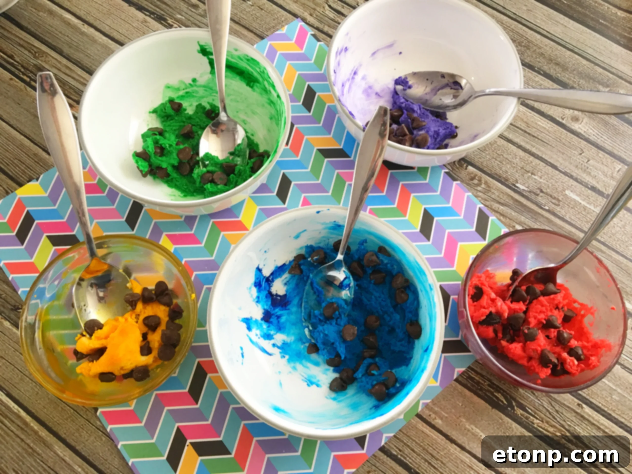 Close-up of different colored cookie dough portions in separate bowls, ready for shaping into rainbow cookies