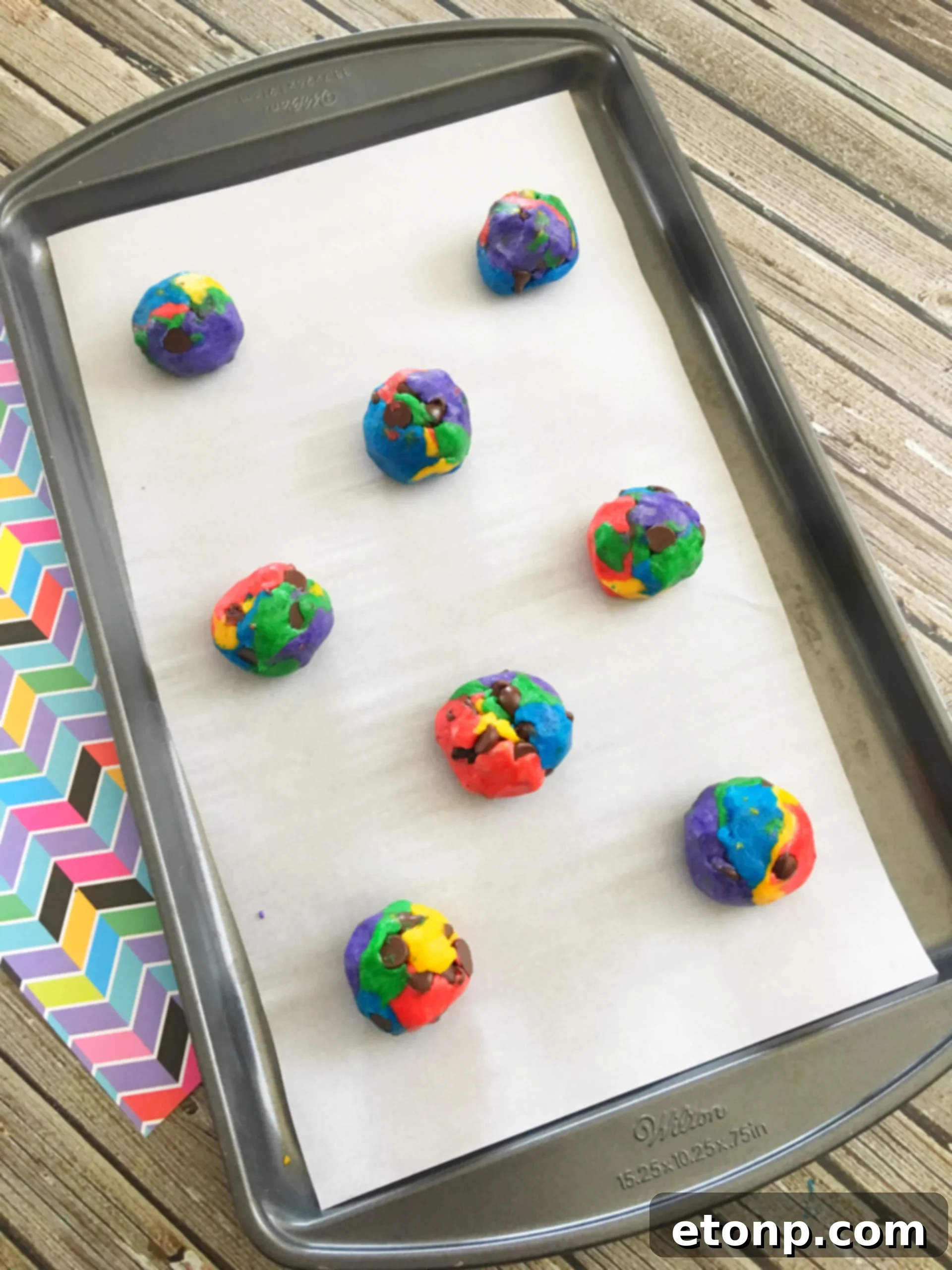 Baked rainbow chocolate chip cookies cooling on a wire rack, displaying their beautiful, thick and slightly puffed shapes