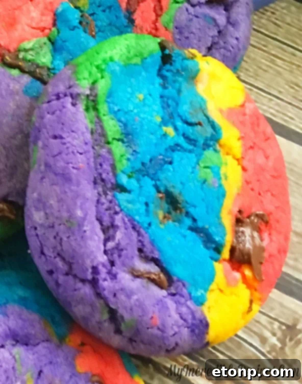 A stack of perfectly baked rainbow chocolate chip cookies, showing off their distinct colorful layers
