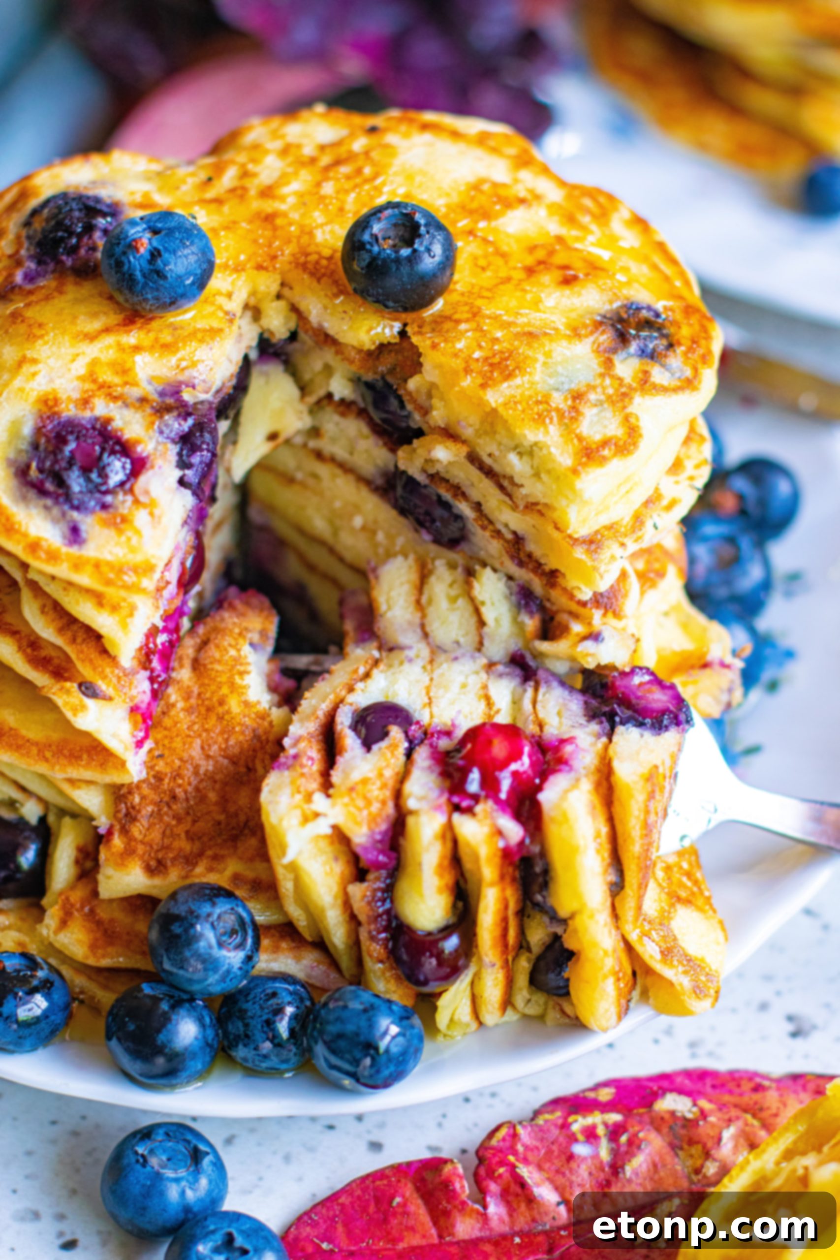 Stack of fluffy blueberry cream cheese pancakes with fresh blueberries and syrup