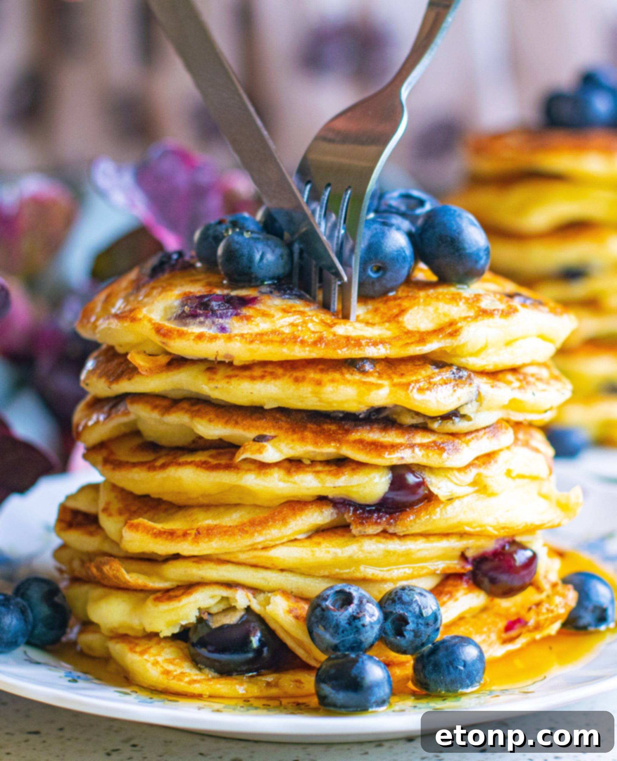 Overhead shot of blueberry cream cheese pancakes with syrup and fresh blueberries