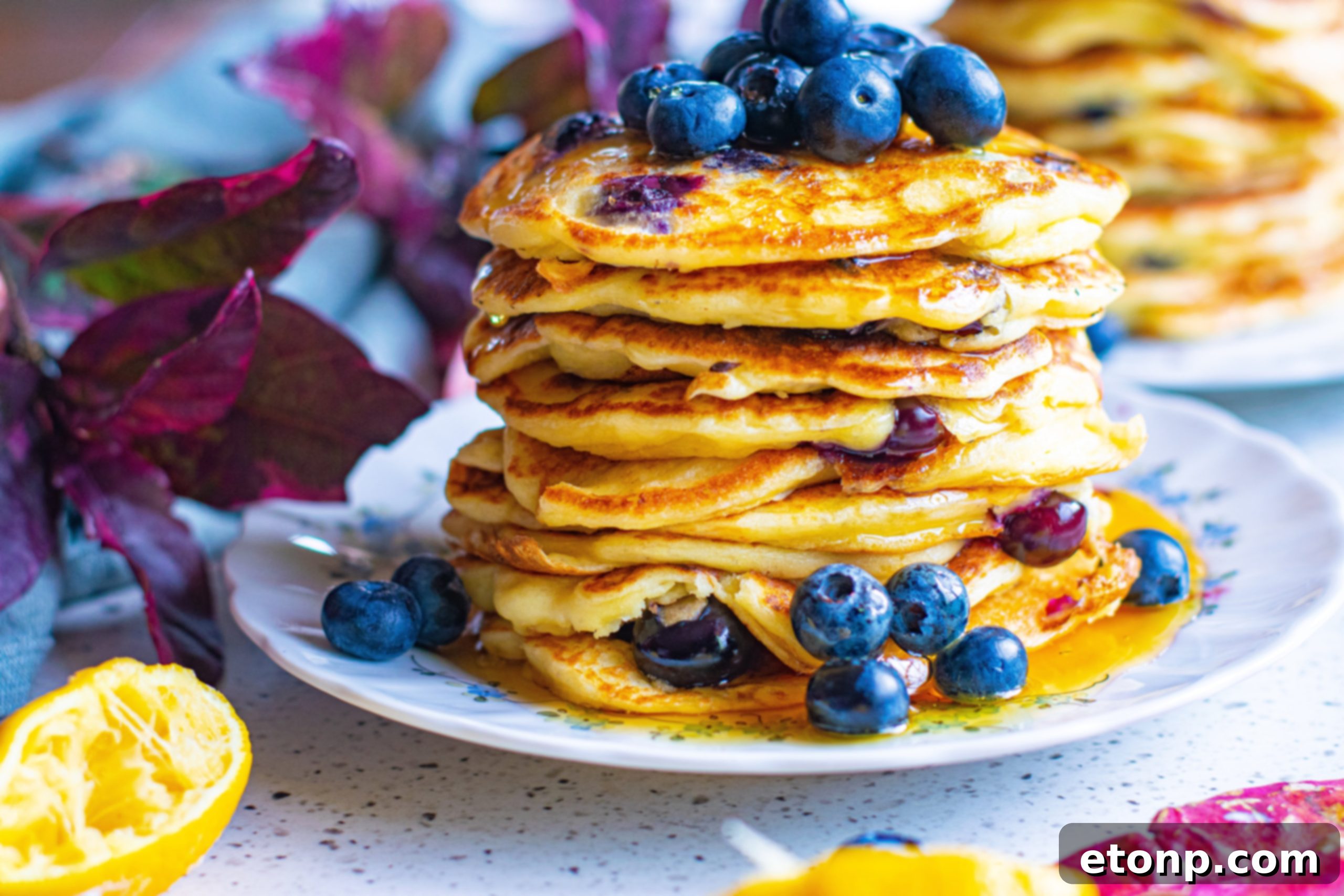 Close-up of a spatula flipping a blueberry cream cheese pancake on a griddle