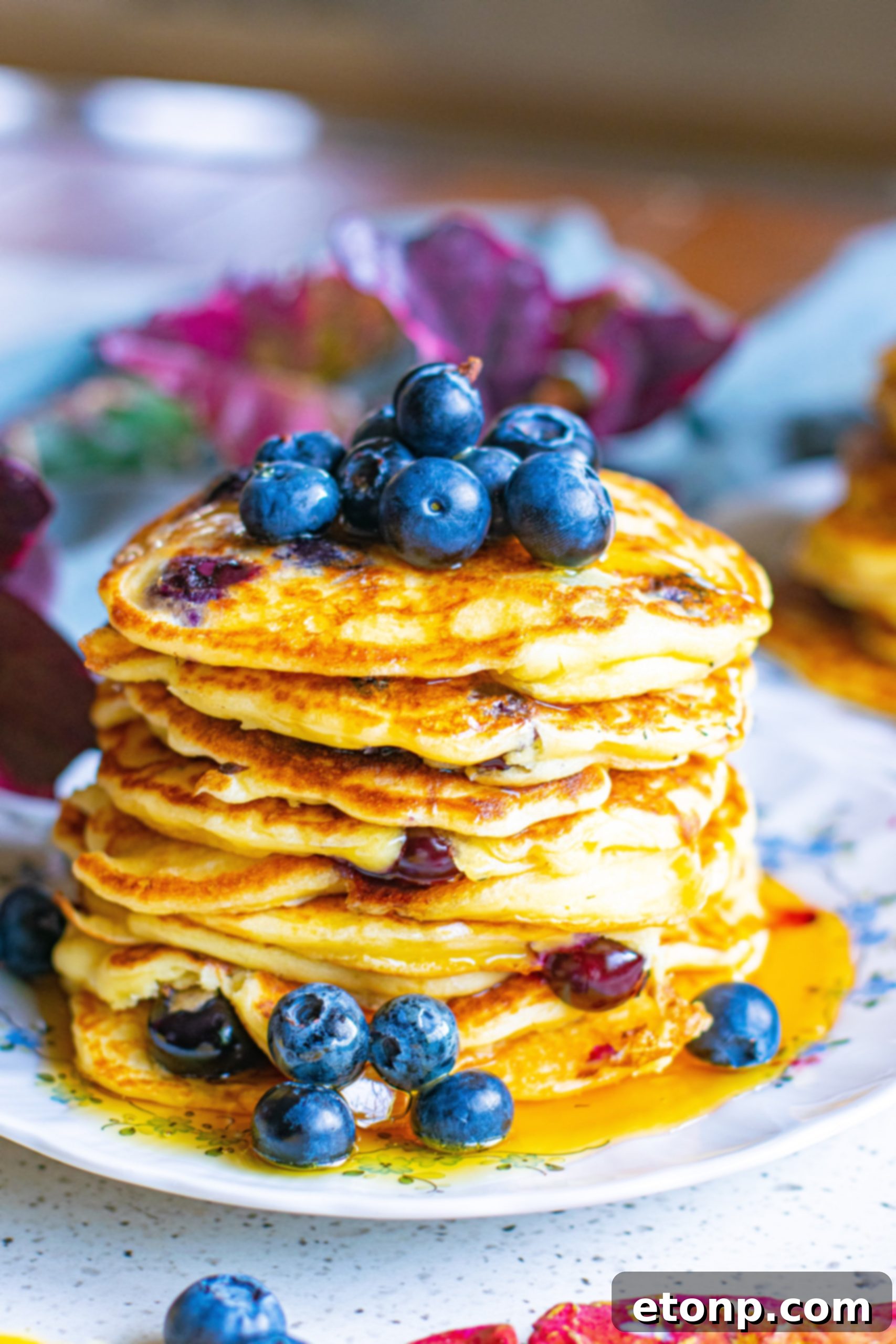A large stack of blueberry cream cheese pancakes on a white plate