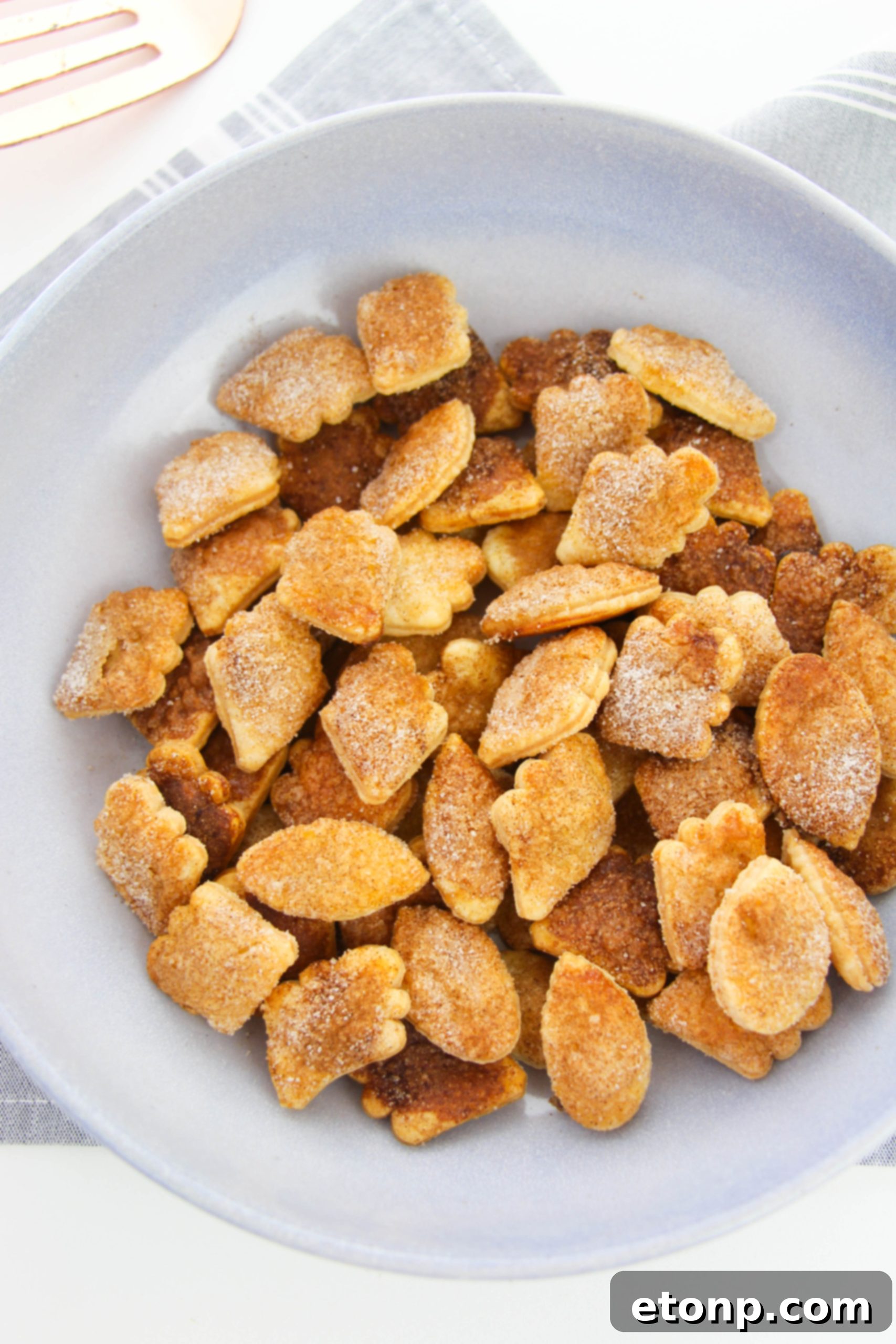 Freshly baked Snickerdoodle Pie Crust Cookies with a golden hue, arranged on a baking sheet lined with parchment paper