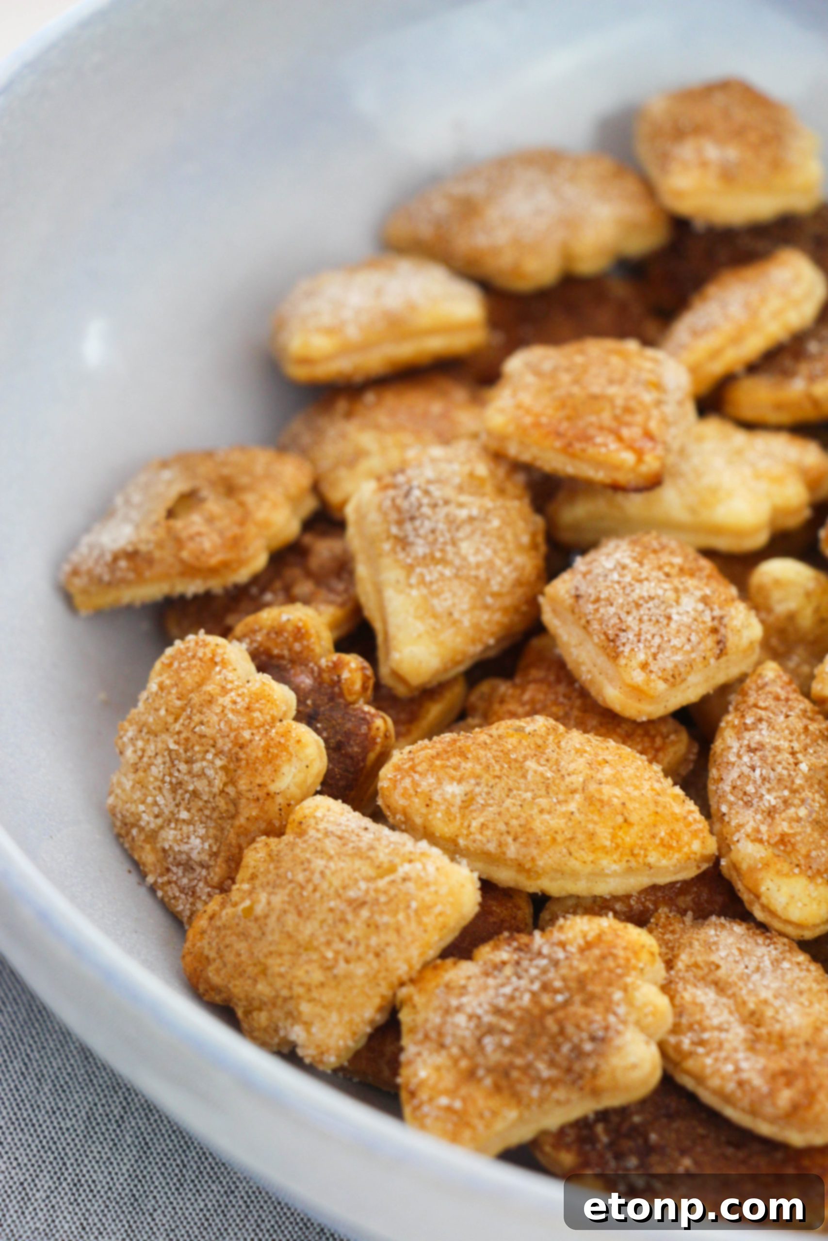 A collection of Snickerdoodle Pie Crust Cookies, some shaped like autumn leaves, artfully arranged on a serving plate