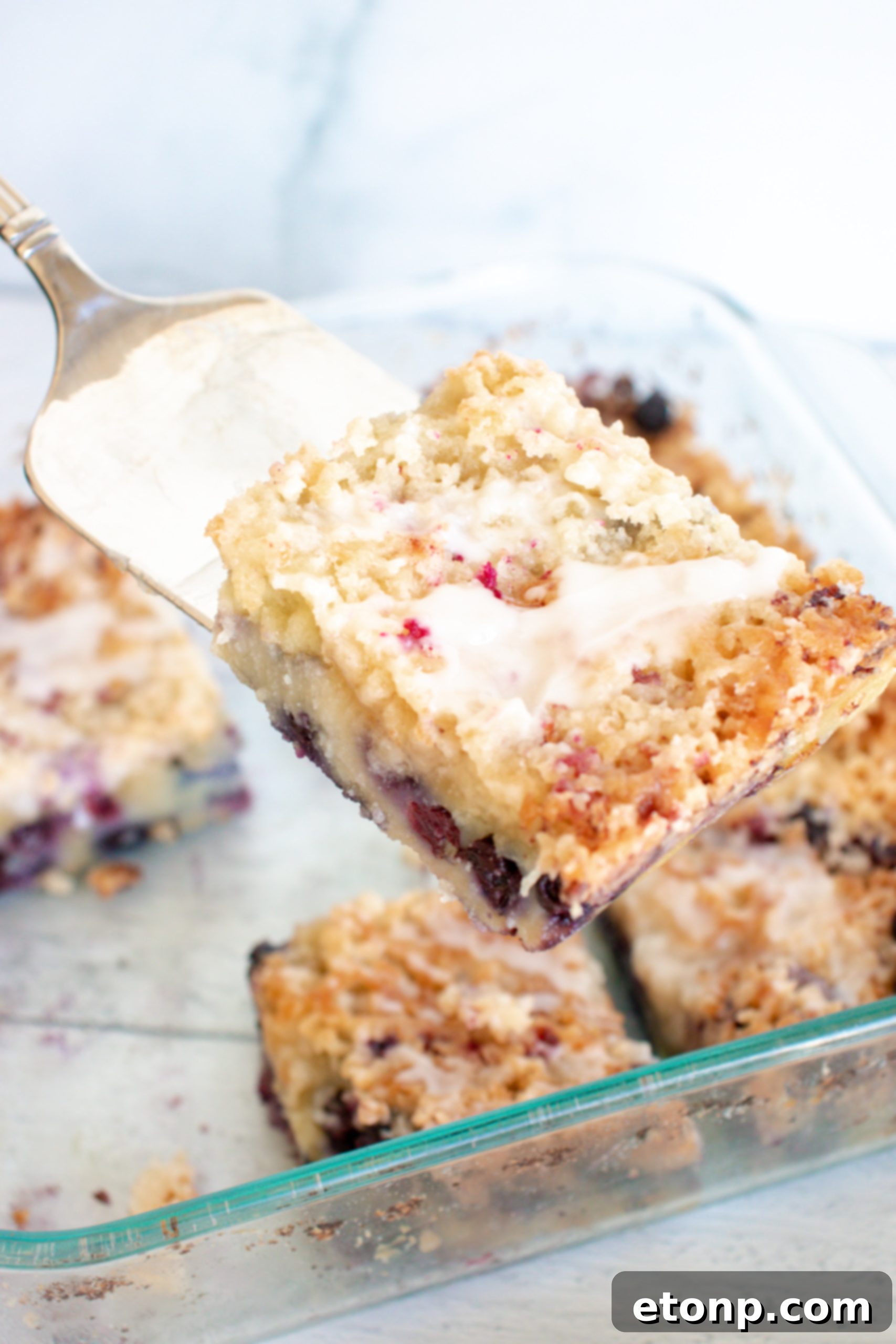 Several blueberries scattered next to a mixing bowl with cake batter, emphasizing the fresh ingredients