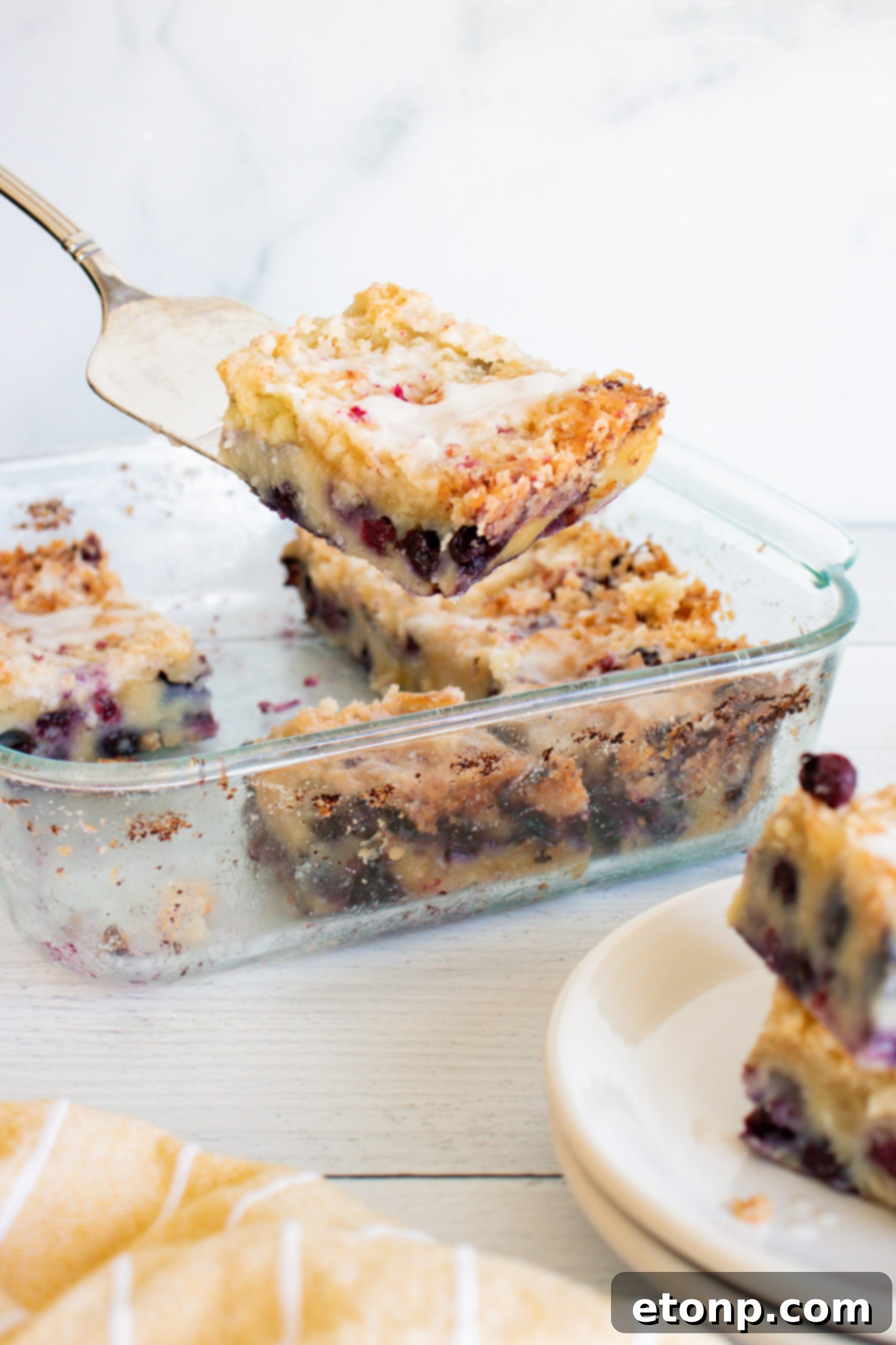 A side view of the blueberry muffin cake, showing the layers of cake, streusel, and glaze