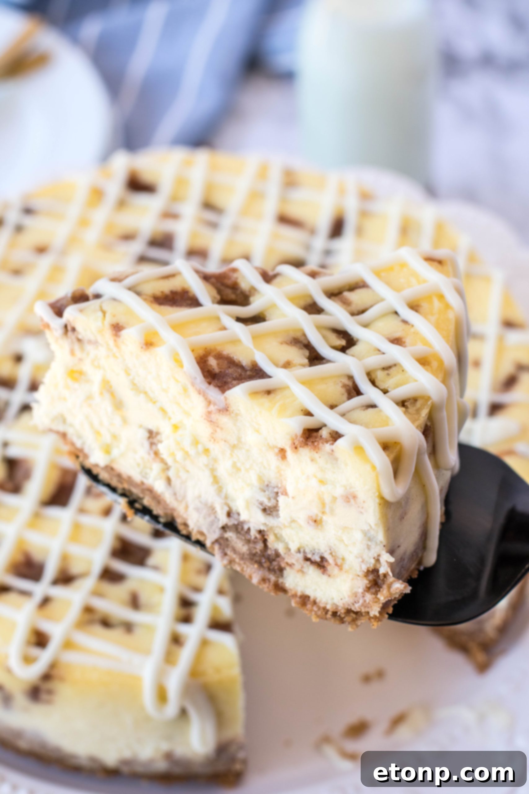 A beautifully baked Cinnamon Roll Cheesecake, sliced to reveal layers of cinnamon swirl within the creamy filling.