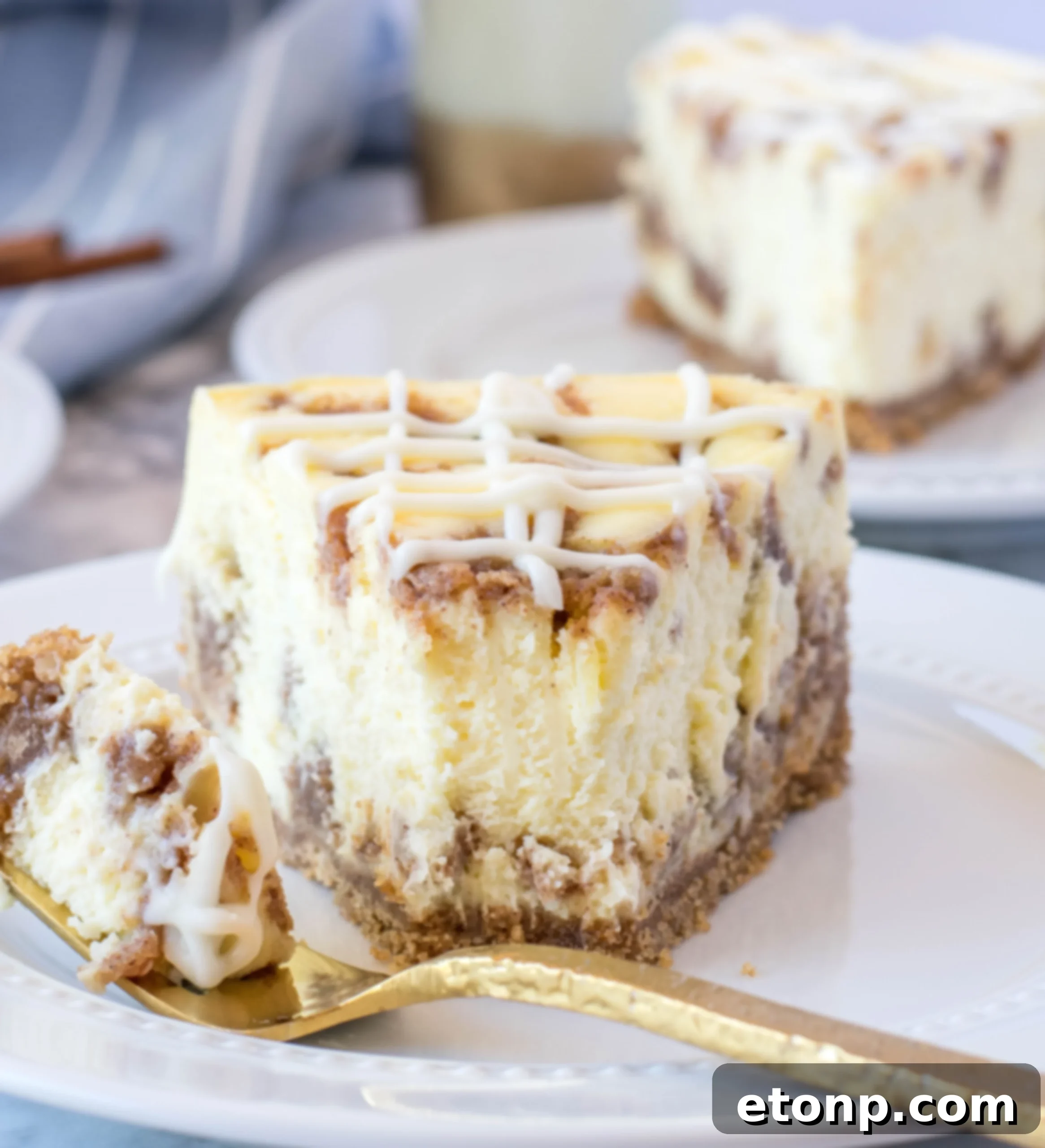 A large, inviting slice of Cinnamon Roll Cheesecake, generously topped with whipped cream and more cream cheese icing.