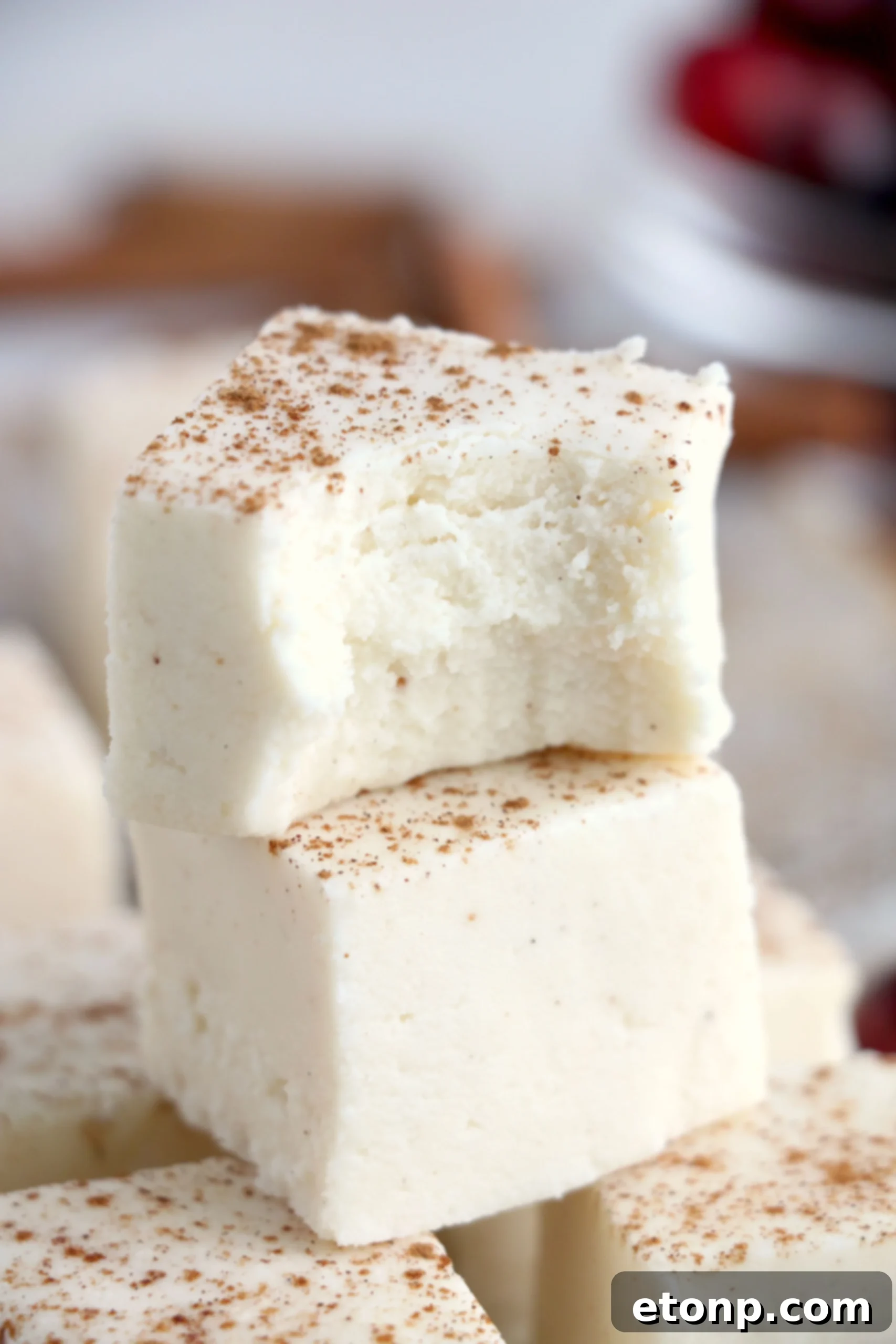 Close-up of creamy eggnog fudge slices with a sprinkle of cinnamon on top.