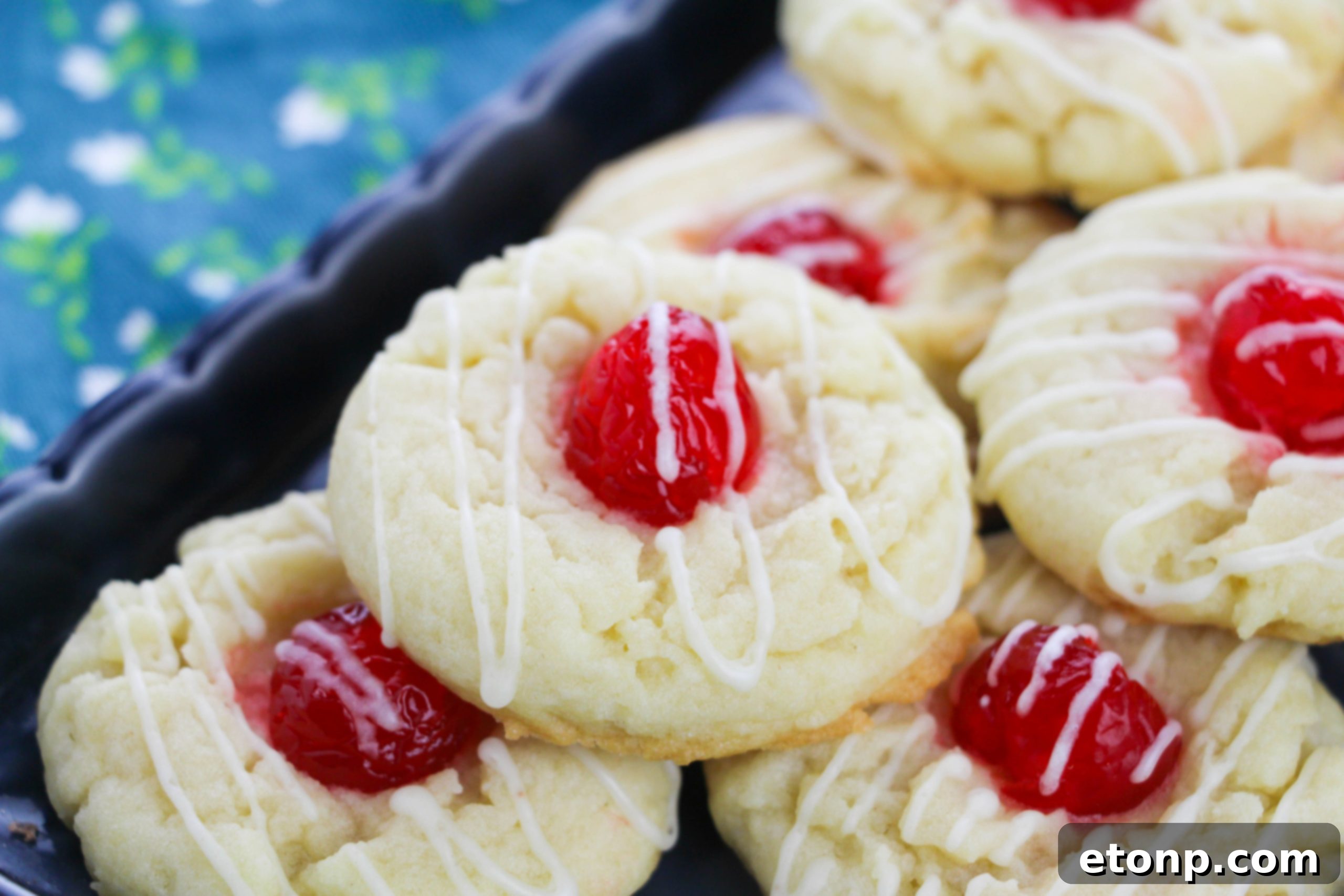 A close-up of an Eggnog Thumbprint Cookie with a perfect maraschino cherry center, ready to be enjoyed.