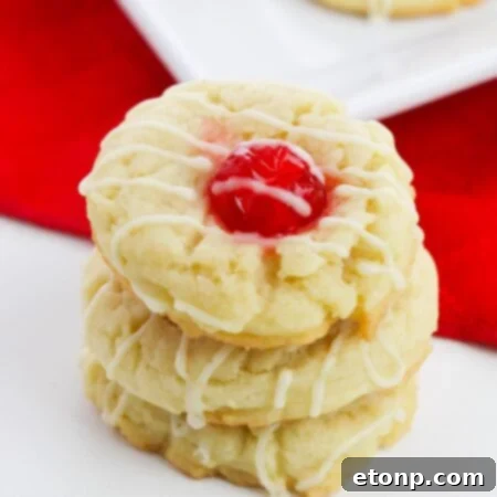 Prominently featured Eggnog Thumbprint Cookie with a cherry center and drizzle.