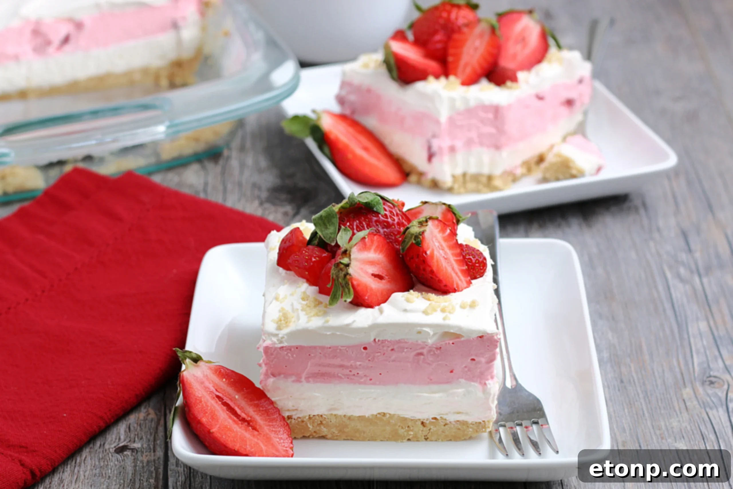 A full pan of the finished Strawberry Cheesecake Lasagna, garnished with fresh strawberries and ready for serving.