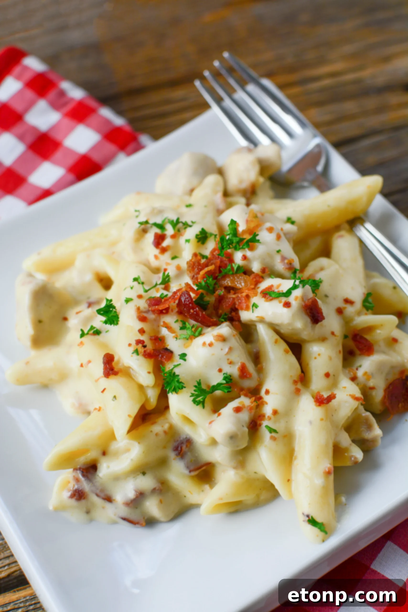 A close-up shot of Instant Pot Crack Chicken Pasta, showing creamy pasta, shredded chicken, and bacon bits.