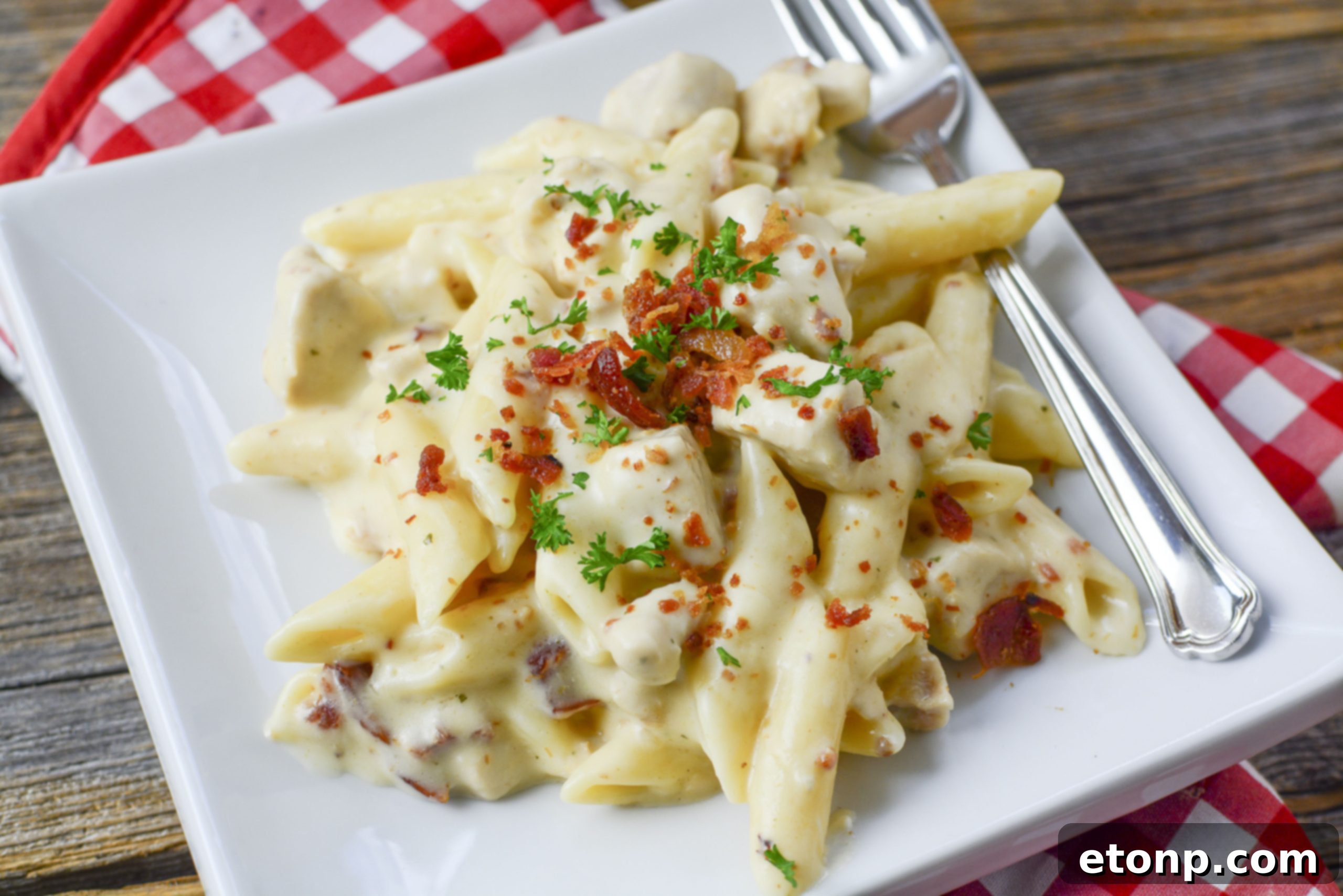 A generous portion of Instant Pot Crack Chicken Pasta in a large serving bowl, with a serving spoon.