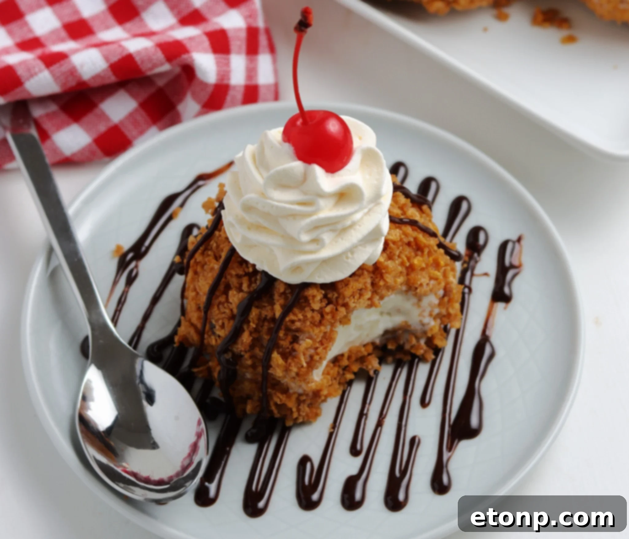 Crispy Fried Ice Cream Delight 7 A plate of freshly fried ice cream, garnished with whipped cream, chocolate syrup, and a maraschino cherry.
