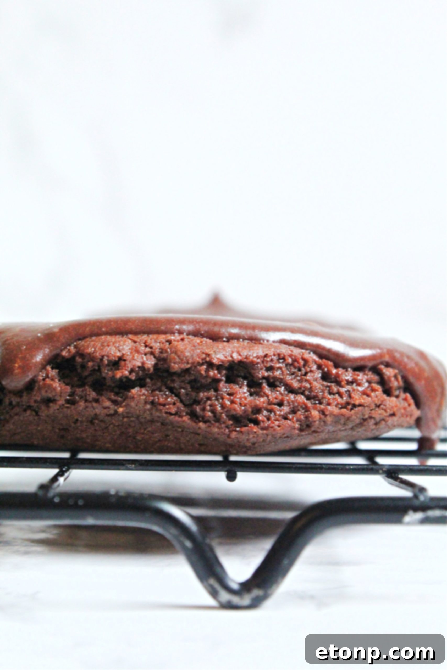 A hand reaching for a freshly baked Texas Sheet Cake Cookie, highlighting its rich, moist texture.