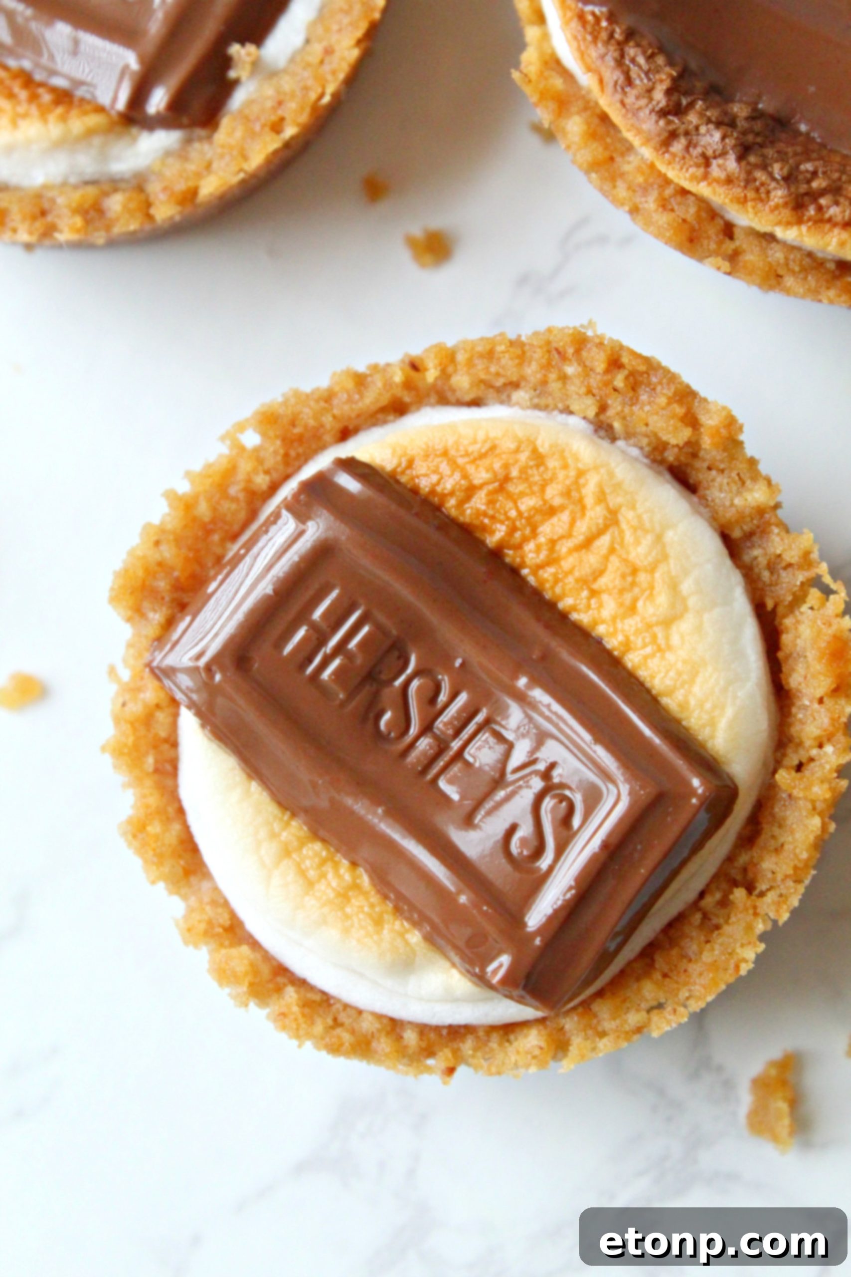 Fireside S'mores Cookie Bites 6 Regular size marshmallows, some cut in half, next to S'mores Cookie Cups ingredients.