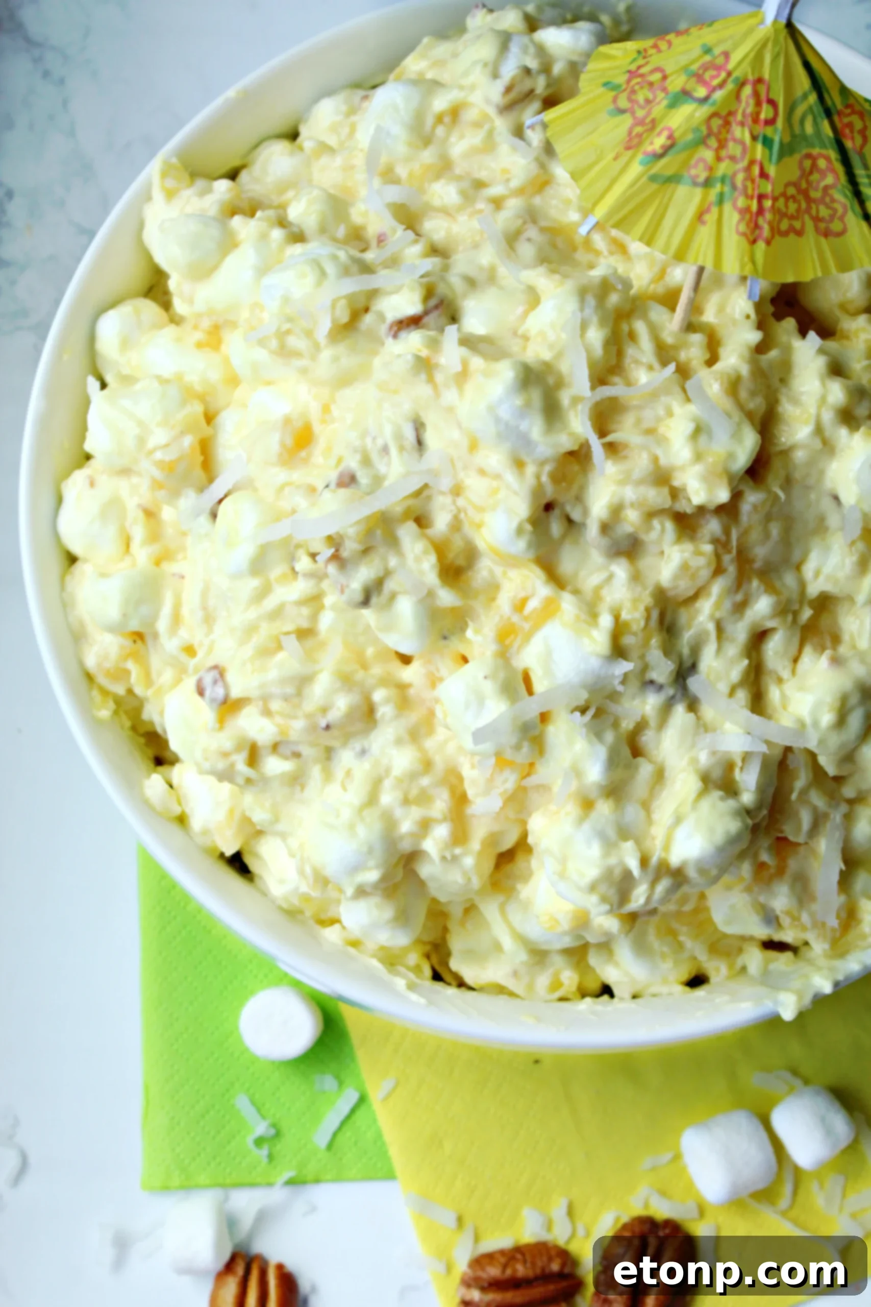 A top-down view of Pina Colada Fluff in a bowl, showcasing its beautiful color and texture, with a serving spoon.