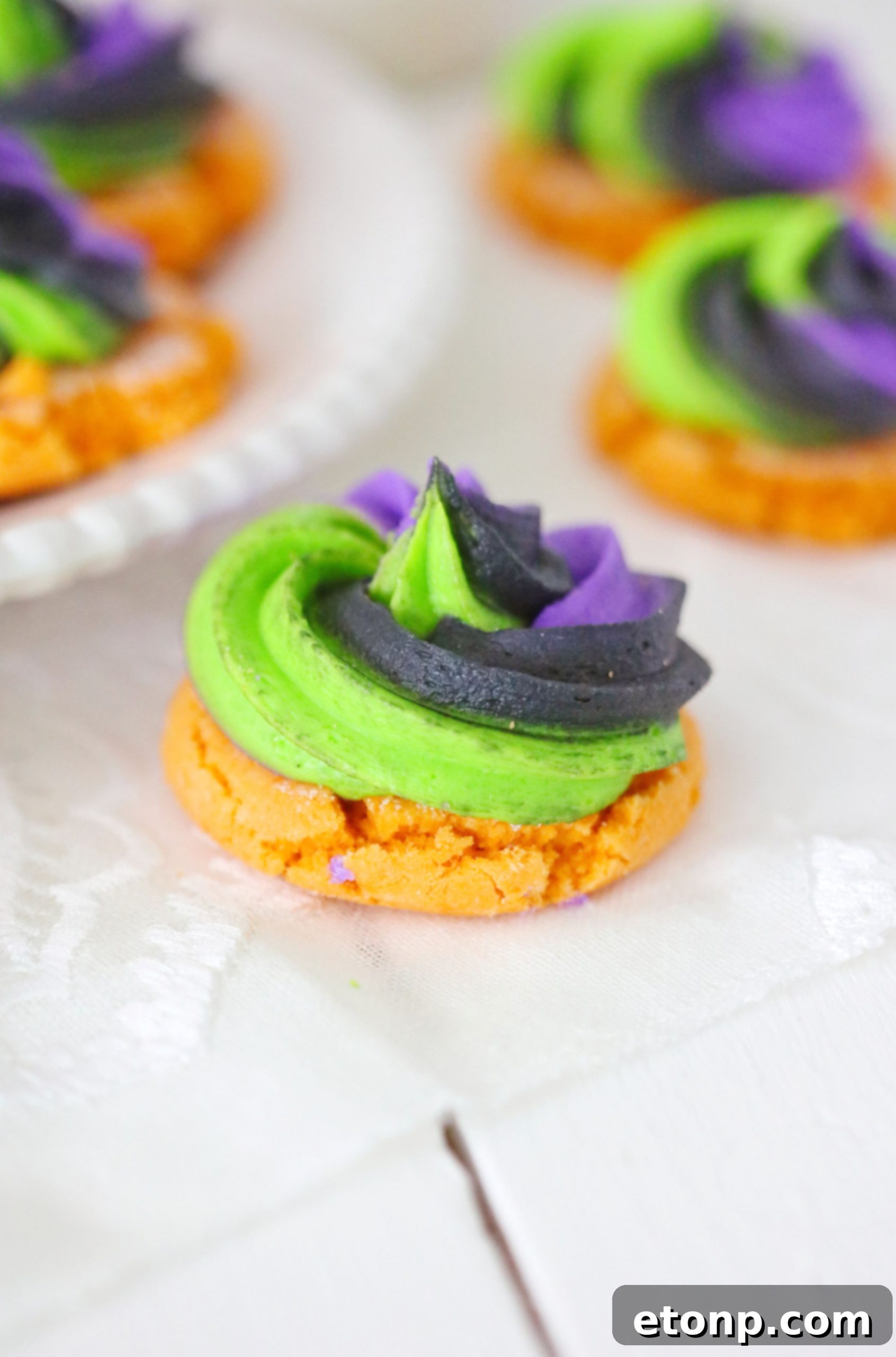 Hand holding a freshly baked and decorated pumpkin sugar cookie, highlighting its appealing design.