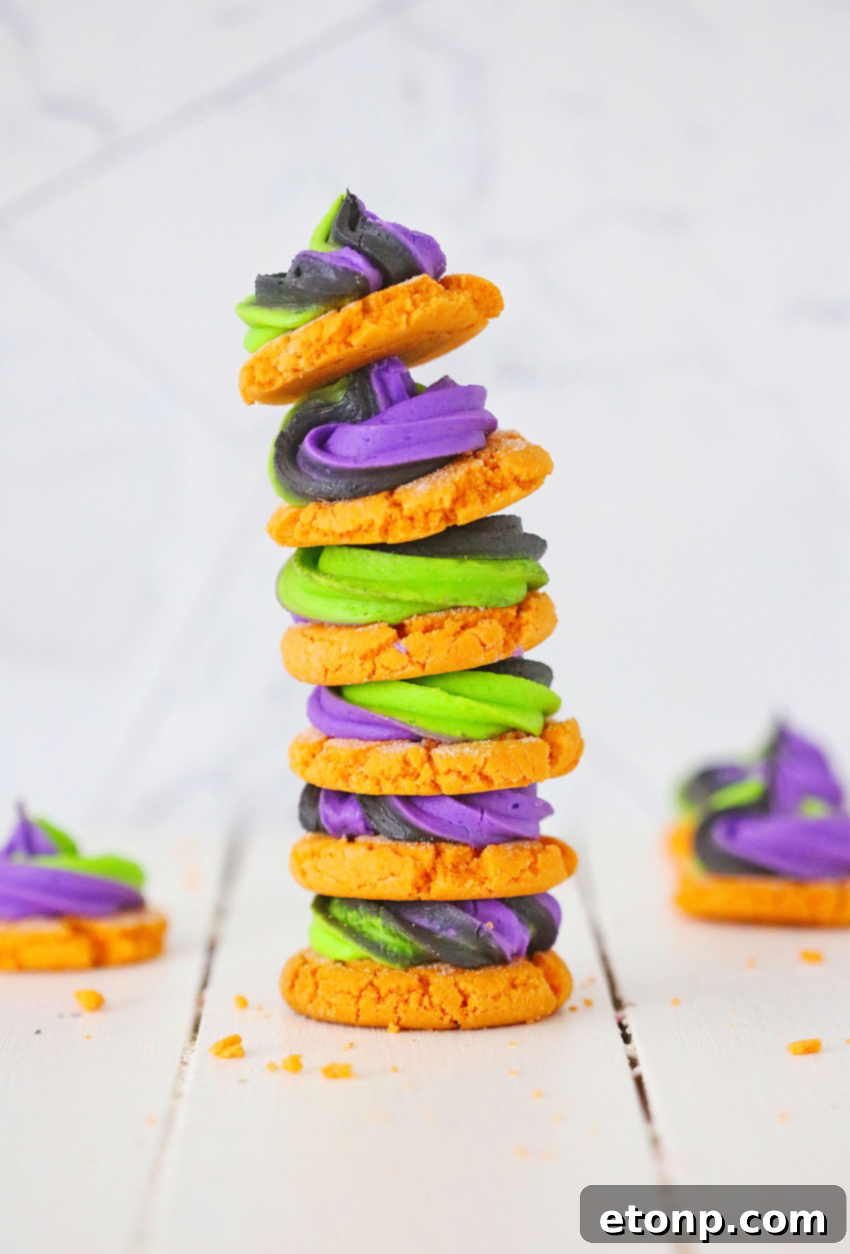 Close-up of a pumpkin sugar cookie with orange, purple, and green swirled frosting, showing intricate details.