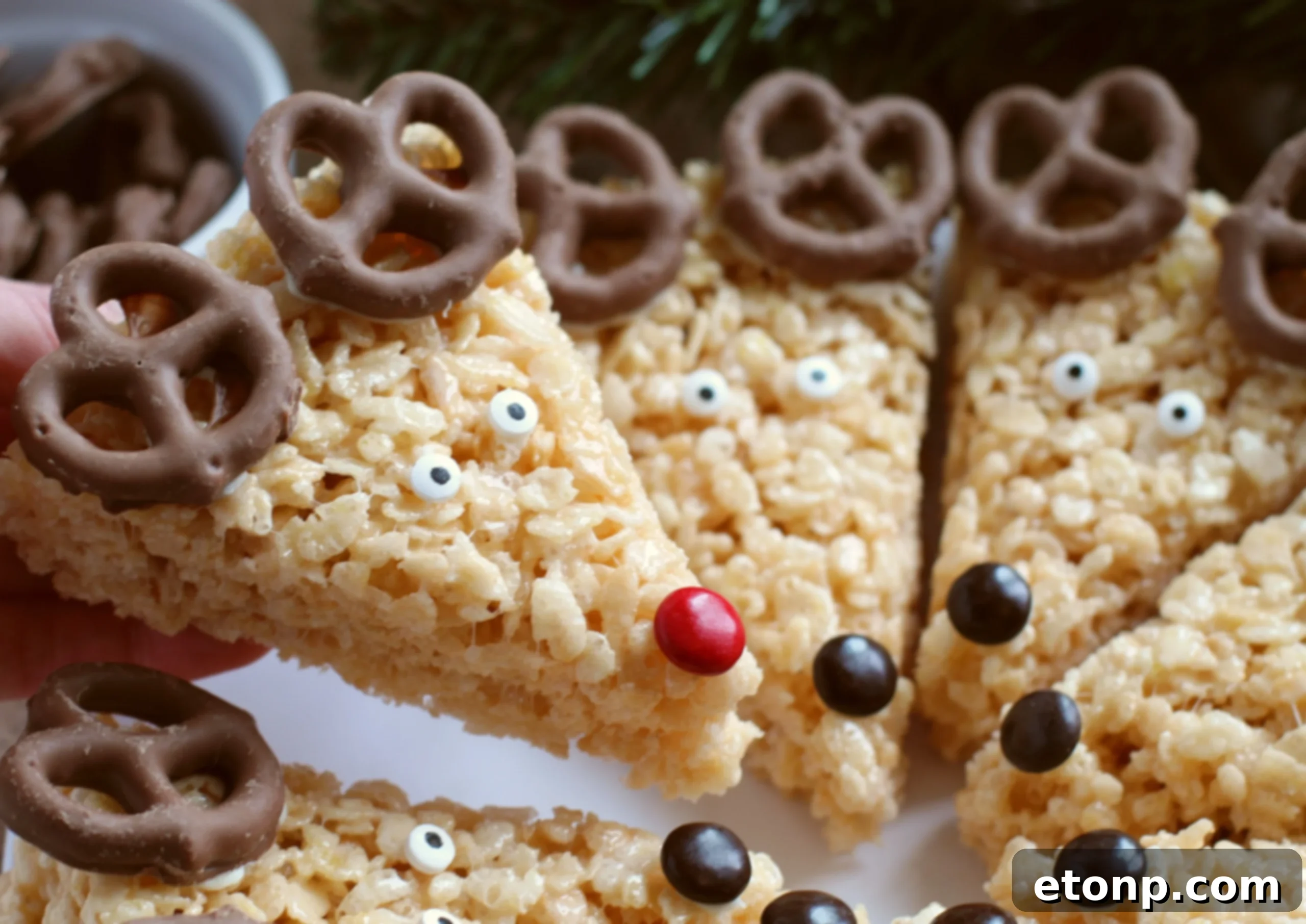 A close-up of a stack of Reindeer Rice Krispie Treats, showcasing the varying expressions of their candy eyes and M&M noses.
