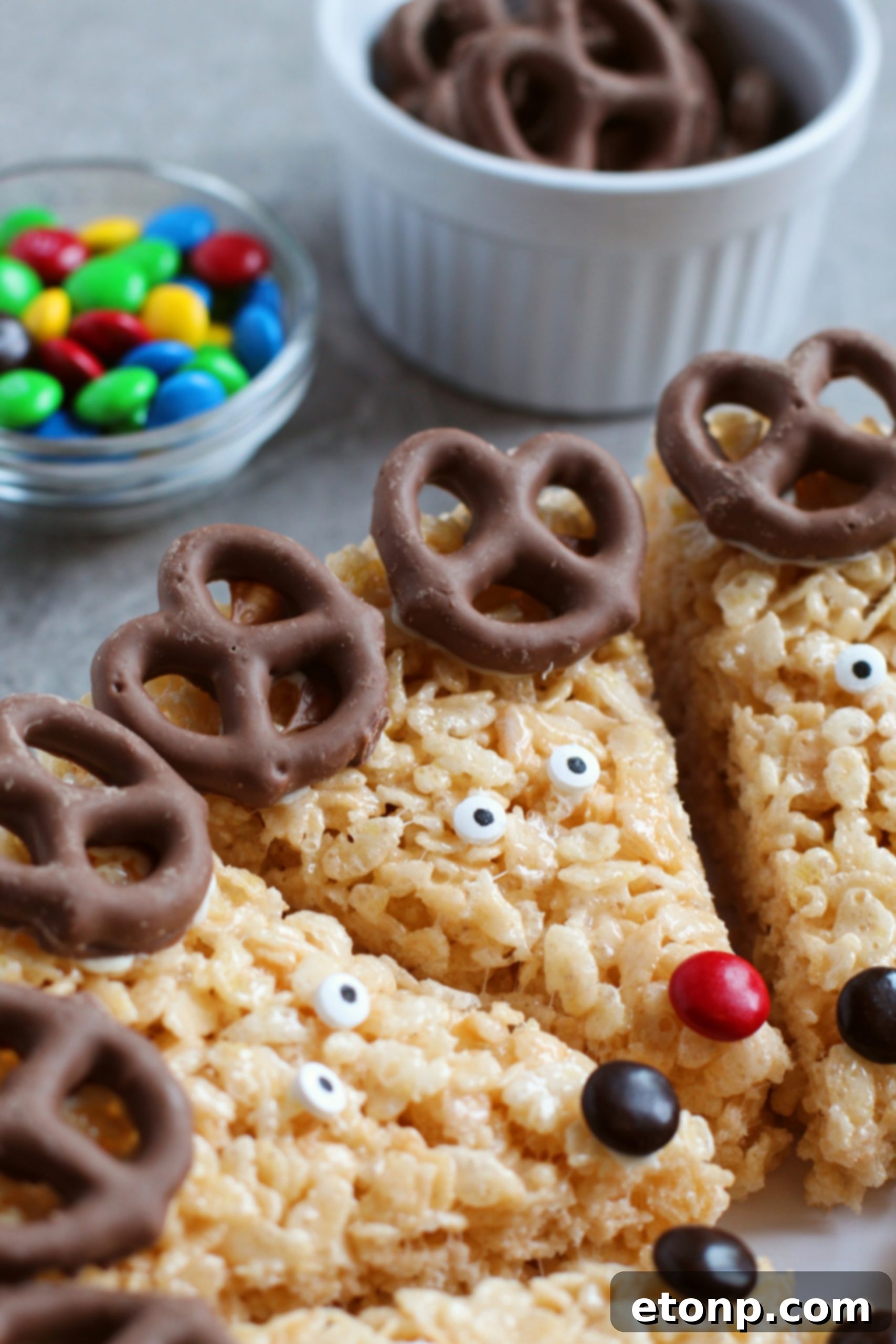 A festive display of a finished Reindeer Rice Krispie Treat, cut and decorated, on a white plate.