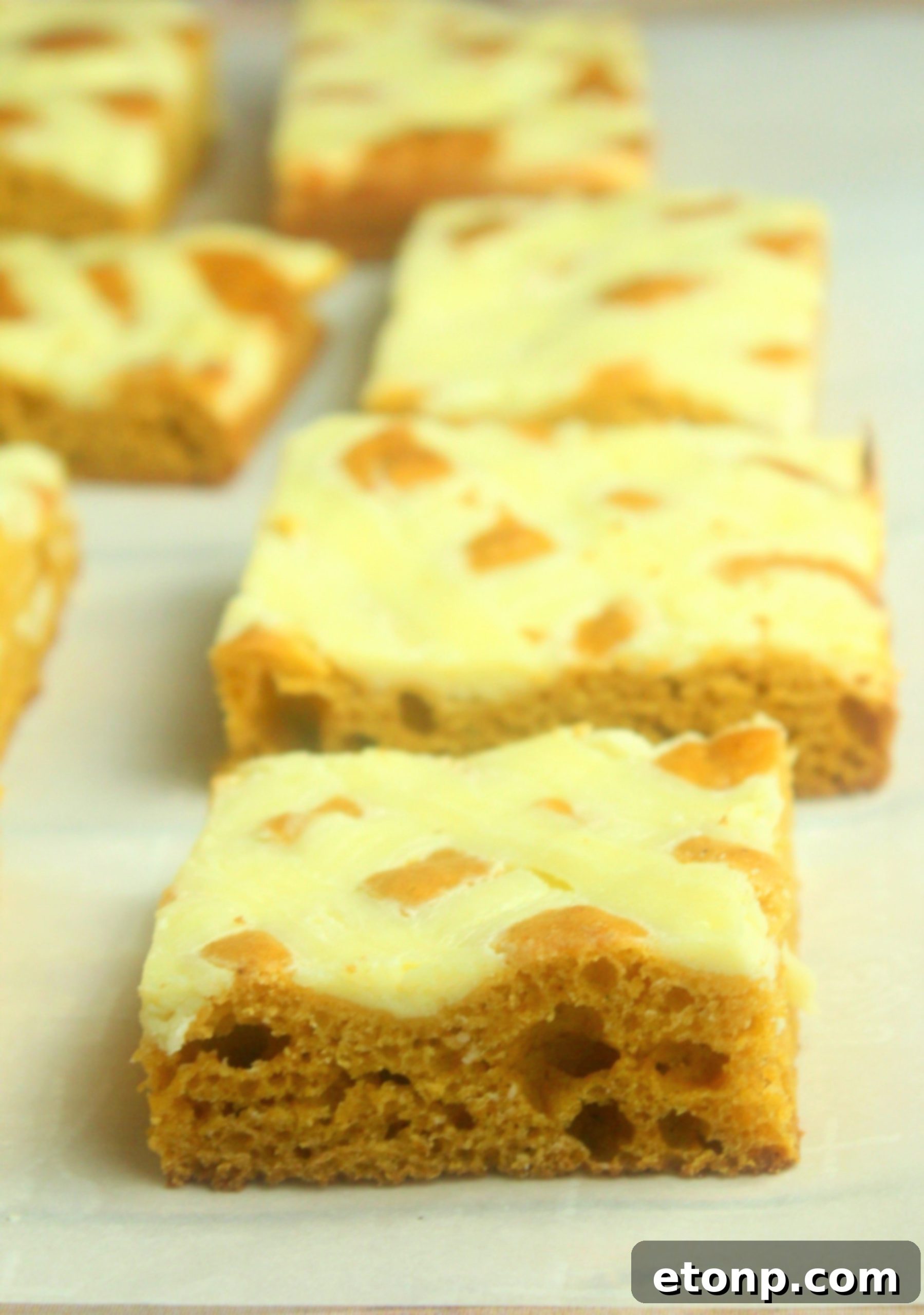 A hand reaching for a piece of Extreme Cream Cheese Pumpkin Bar, highlighting its inviting texture.