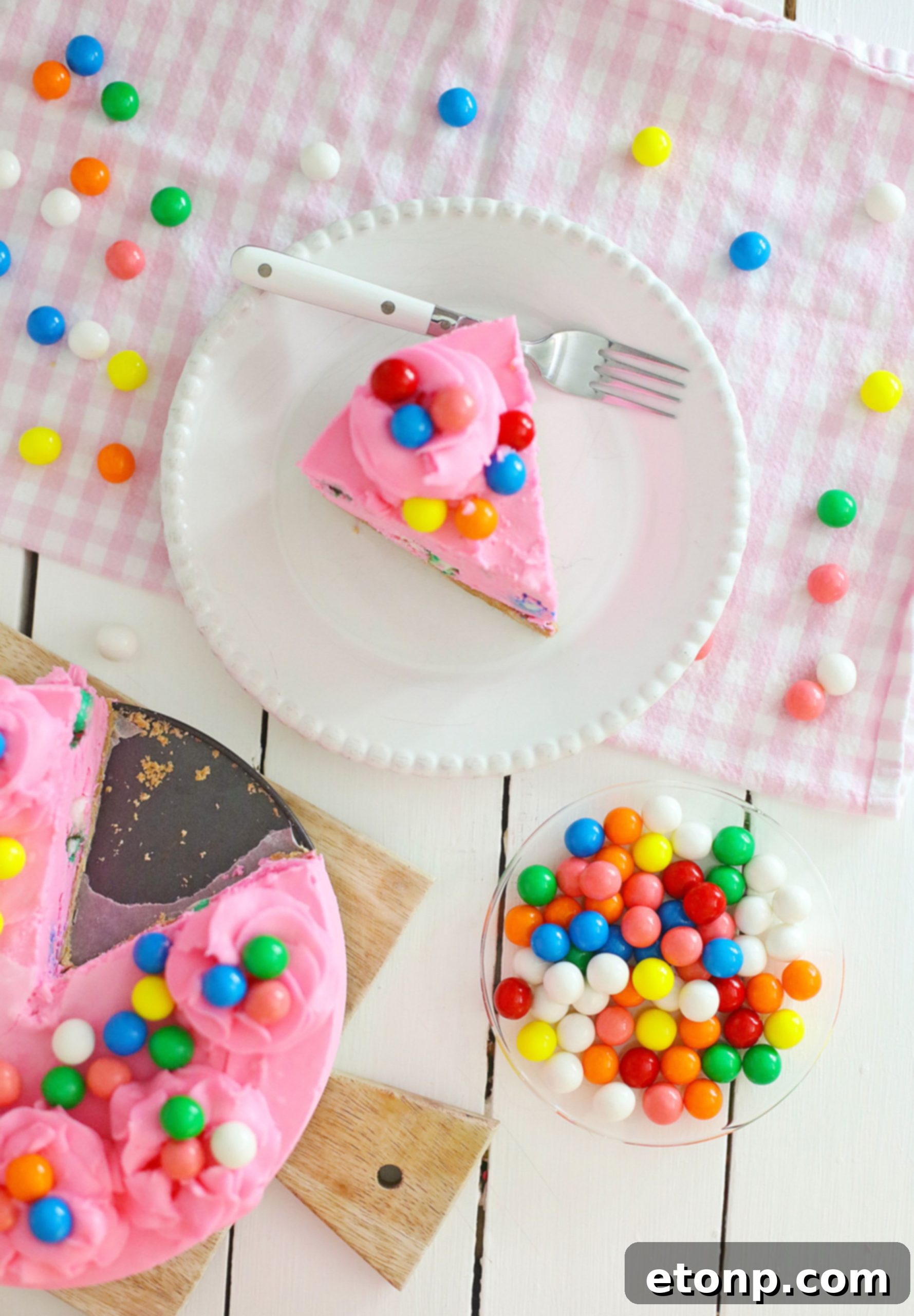 A full Bubblegum Cheesecake on a stand, with a few slices already cut, ready to be enjoyed.