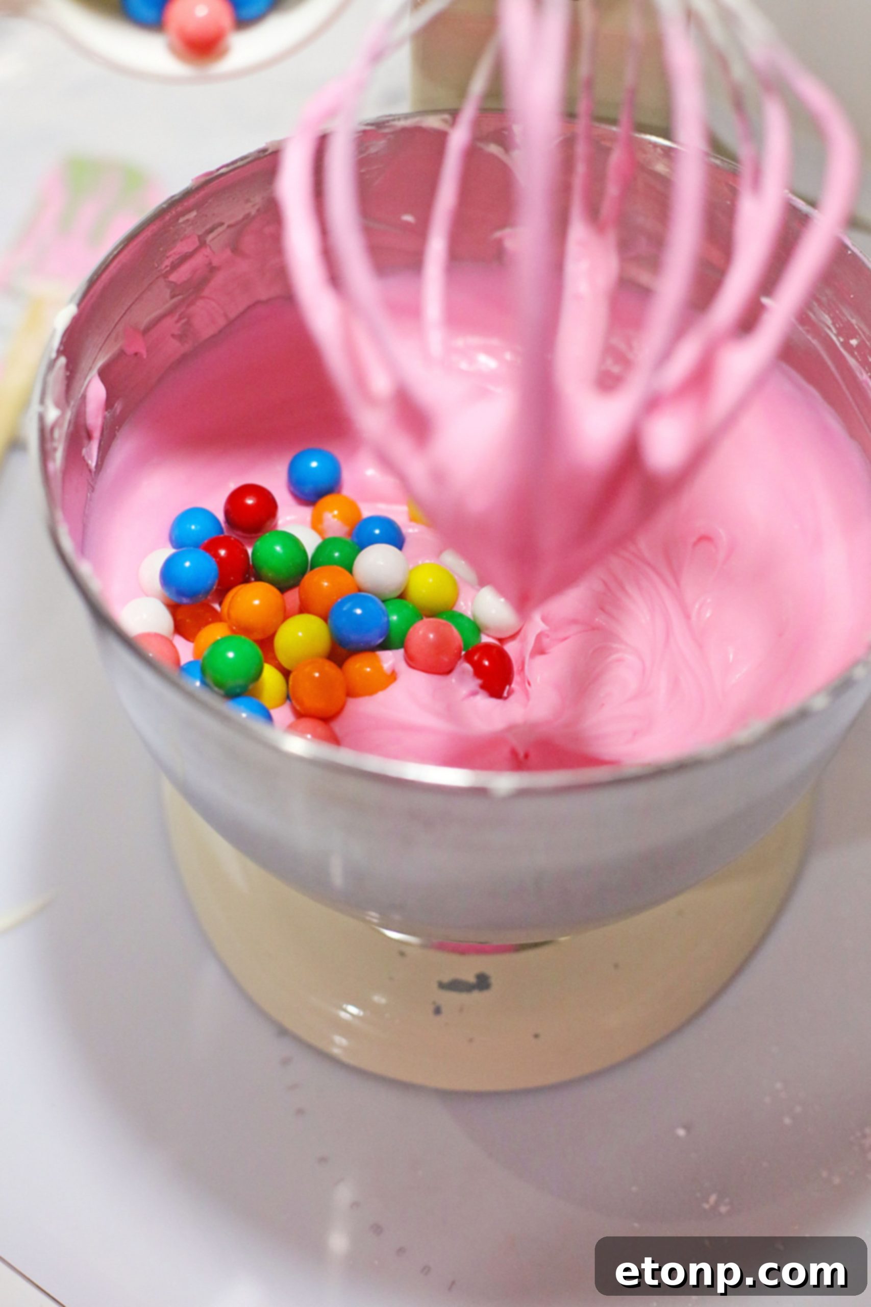 Close-up of the smooth, pink cheesecake batter being mixed in a bowl.