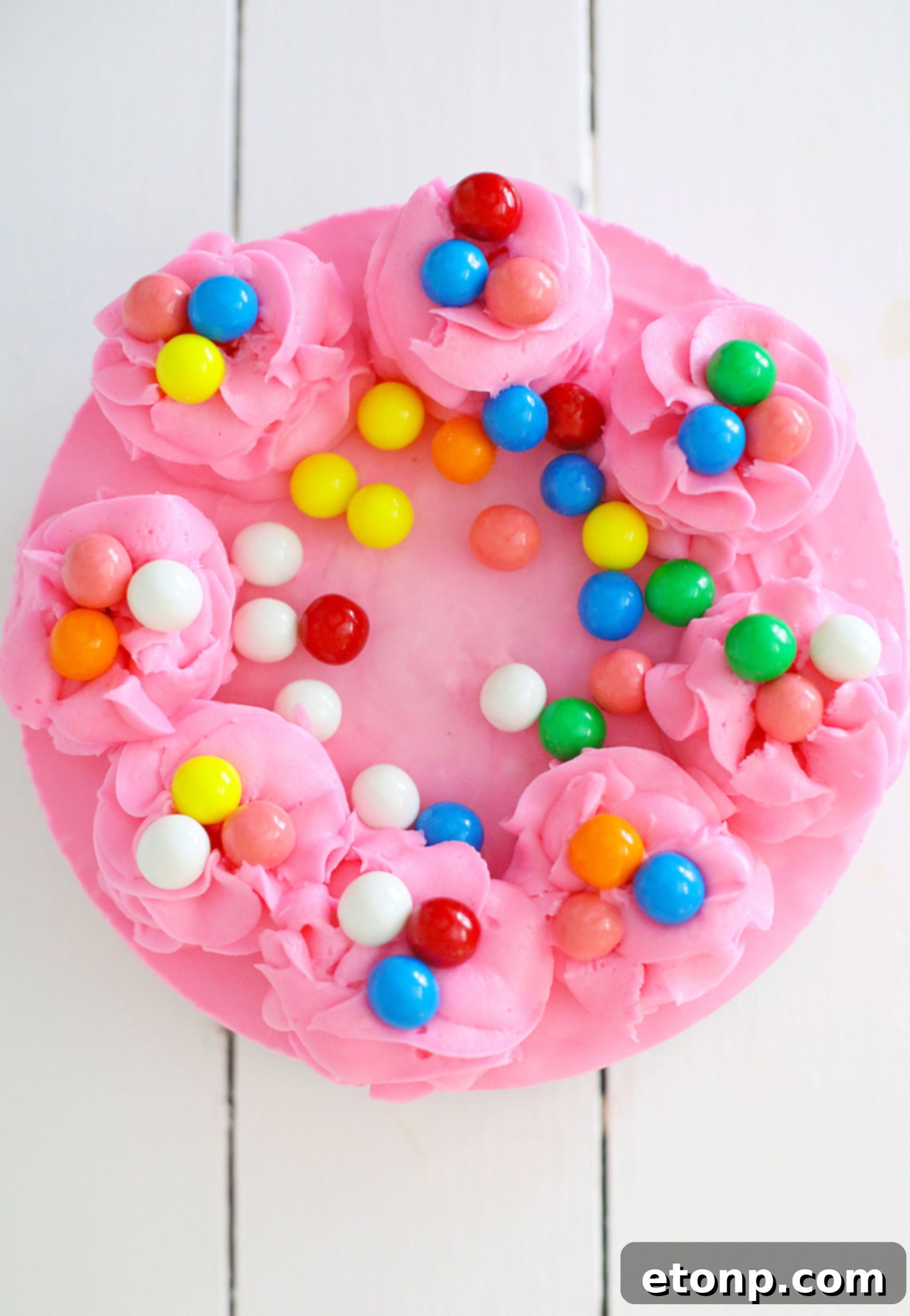 The finished Bubblegum Cheesecake, beautifully decorated with pink frosting swirls and more gumballs, ready to be served.