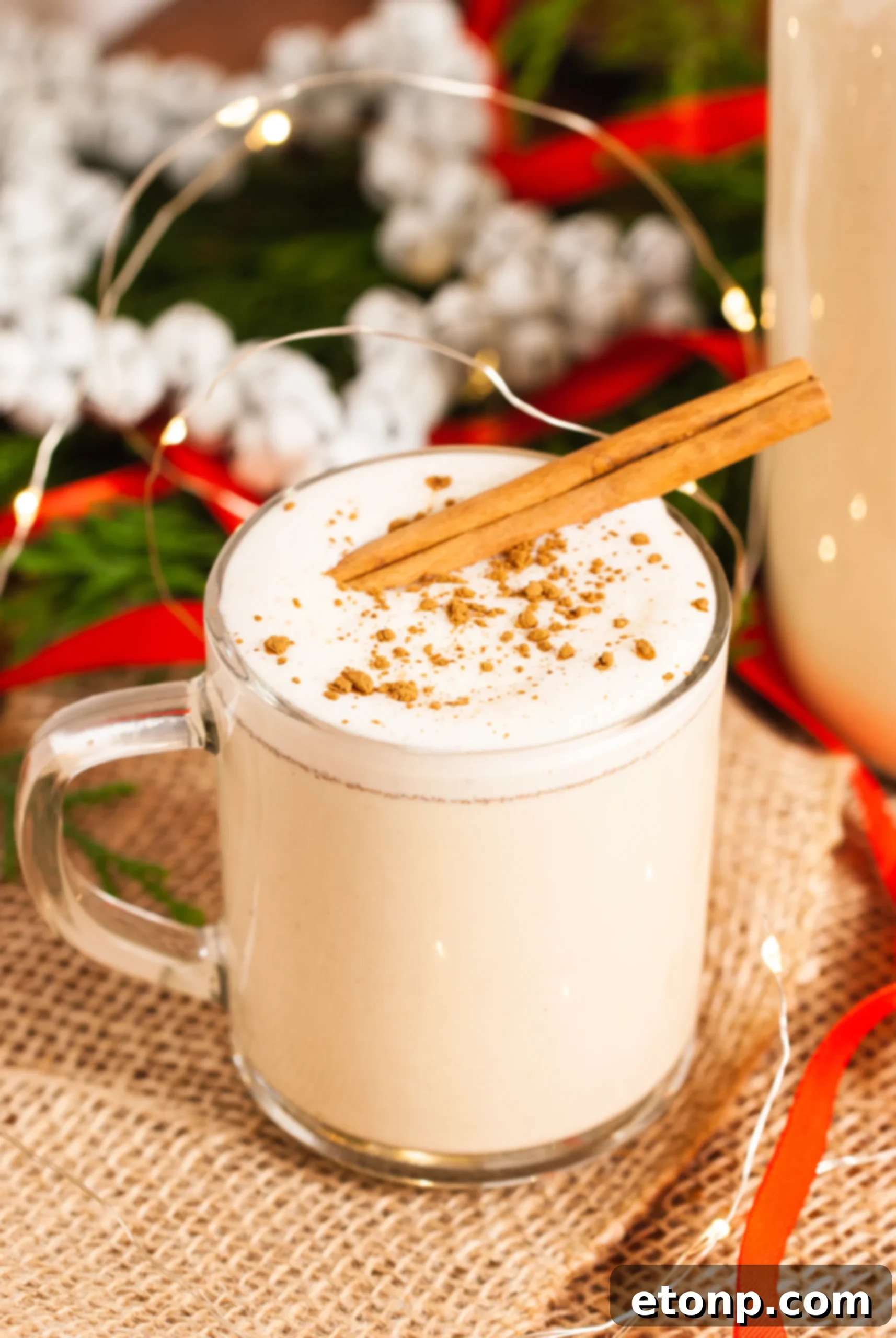 A beautifully garnished glass of homemade eggnog with whipped cream and cinnamon stick, ready for the holidays.