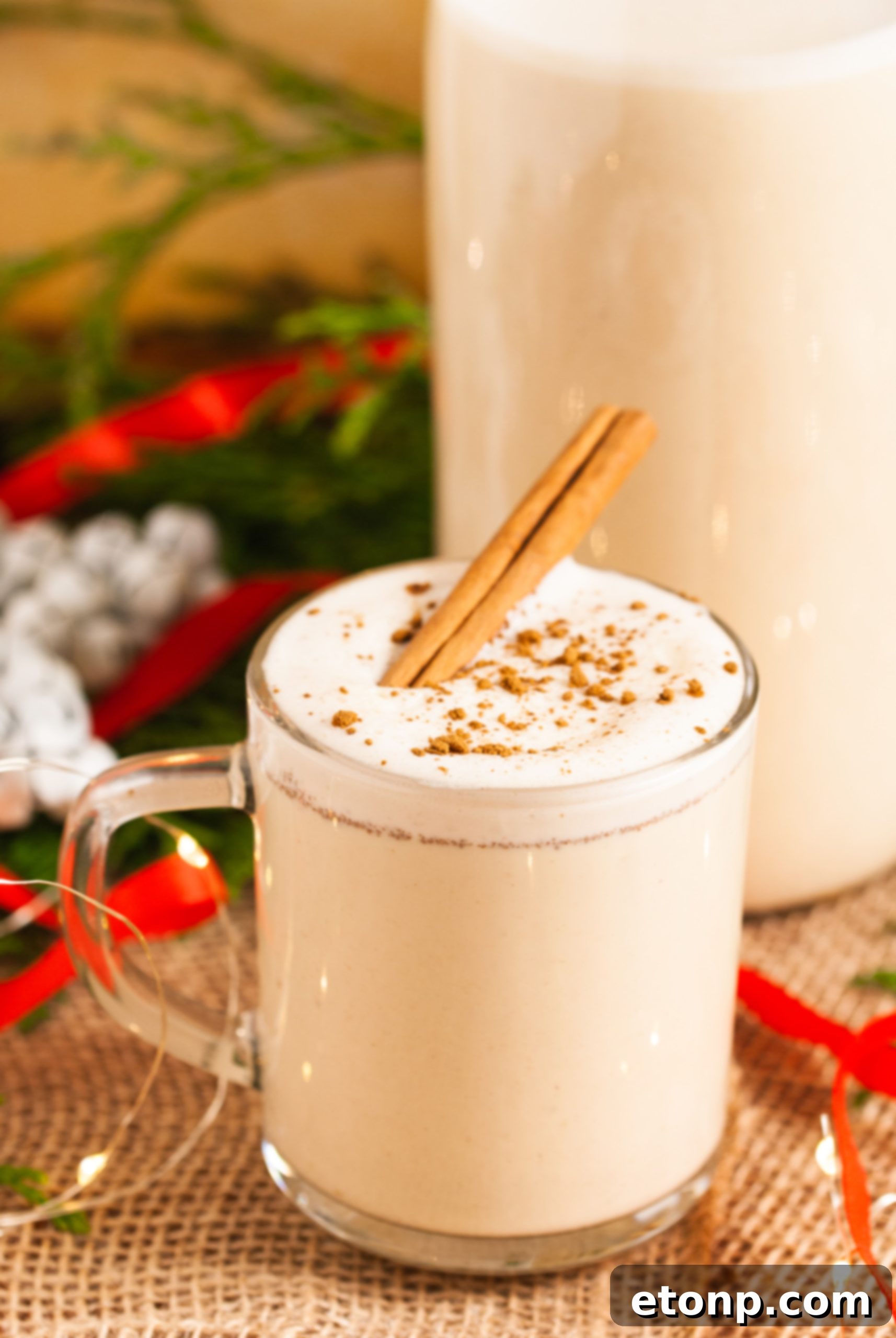 Various eggnog ingredients, including whole spices, eggs, and dairy, are artfully arranged.