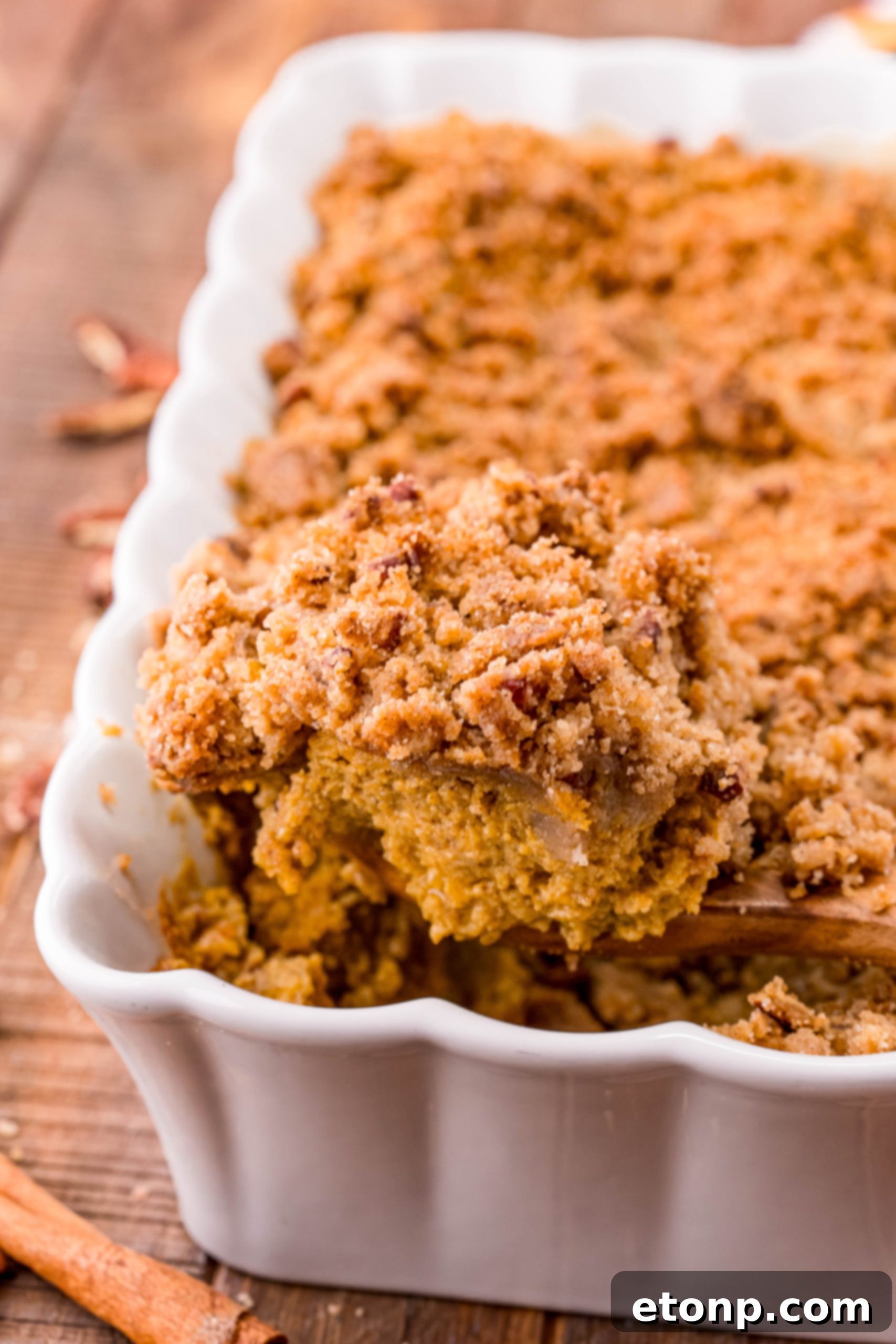 A side view of the Pumpkin Pie Crisp, revealing the thick, creamy pumpkin layer underneath the crumbly topping.