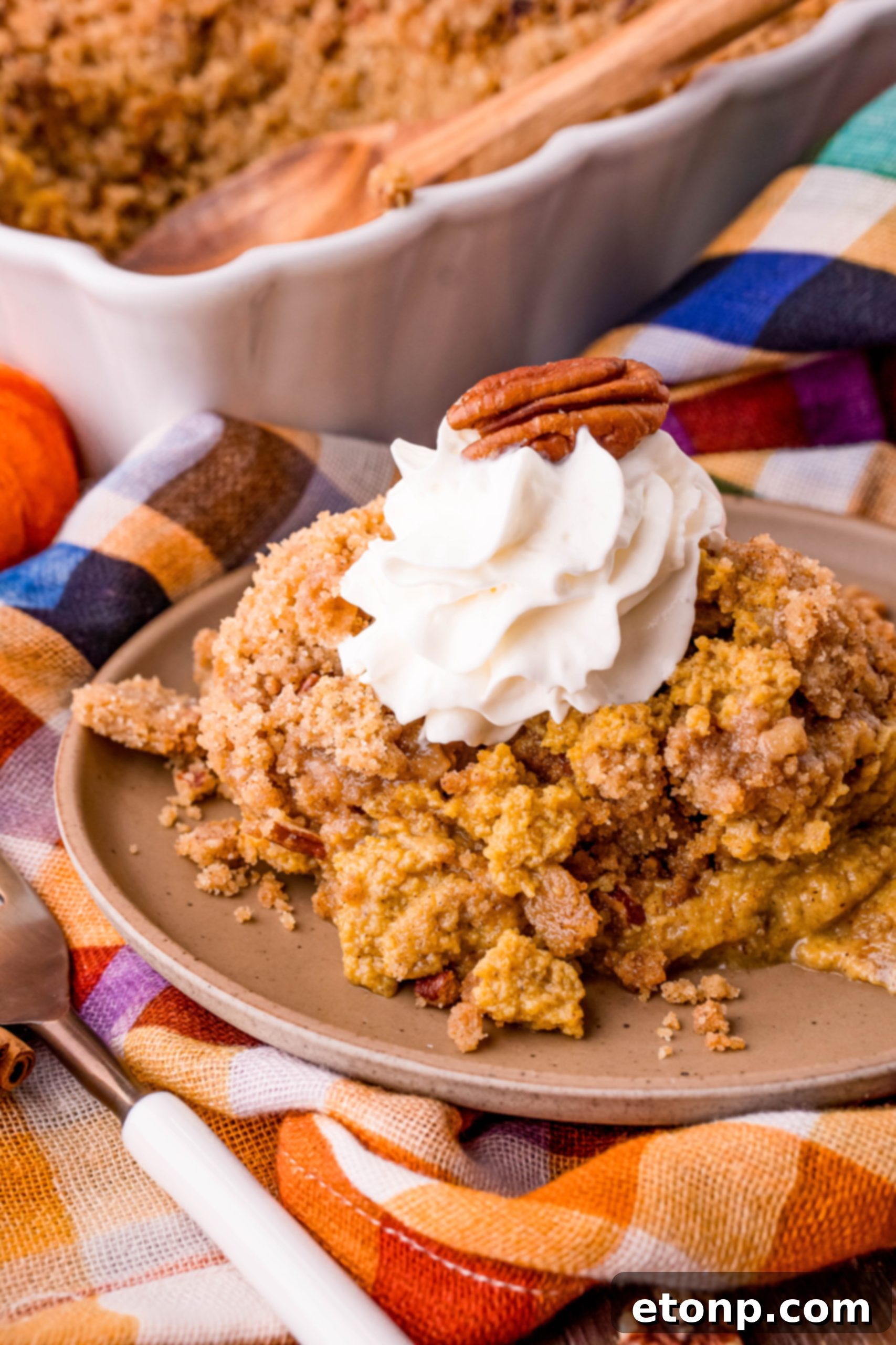 A slice of Pumpkin Pie Crisp topped with a scoop of vanilla ice cream, ready to be served.