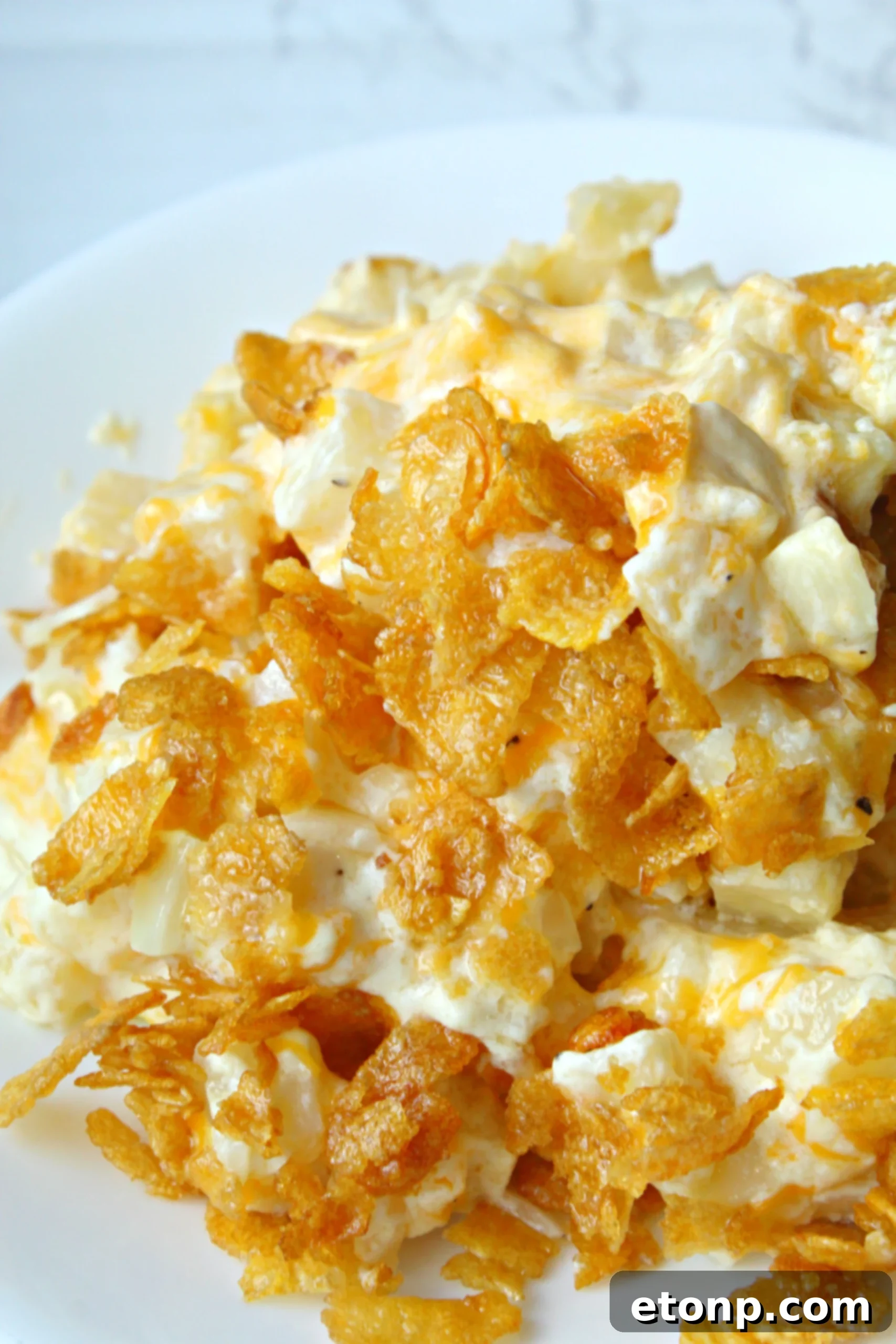 A close-up of a serving of Funeral Potatoes, garnished with fresh parsley.