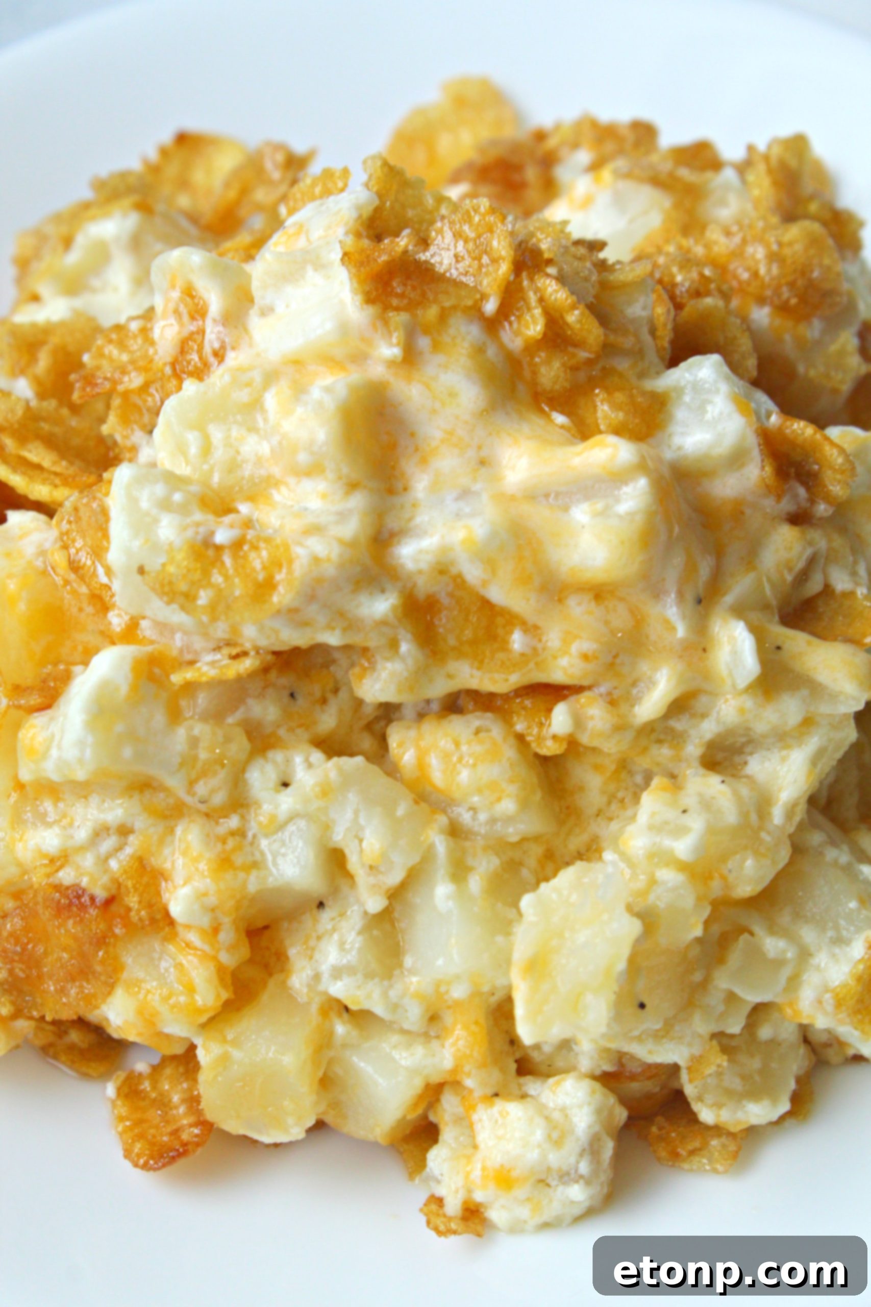 A serving of Funeral Potatoes on a plate with a fork, showing its delicious texture.