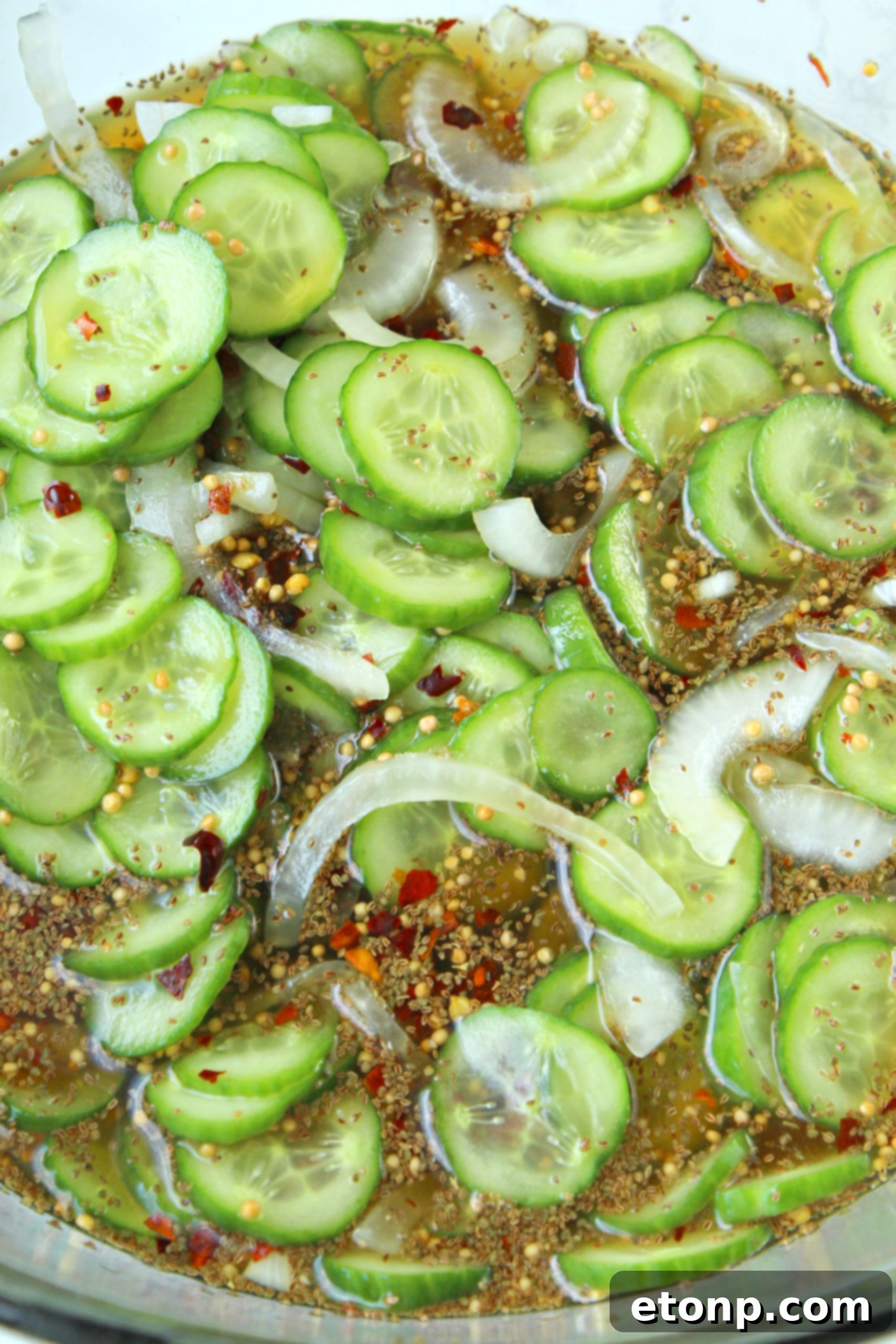 Two hands carefully slicing fresh pickling cucumbers on a wooden cutting board, preparing them for the homemade bread and butter pickle recipe.