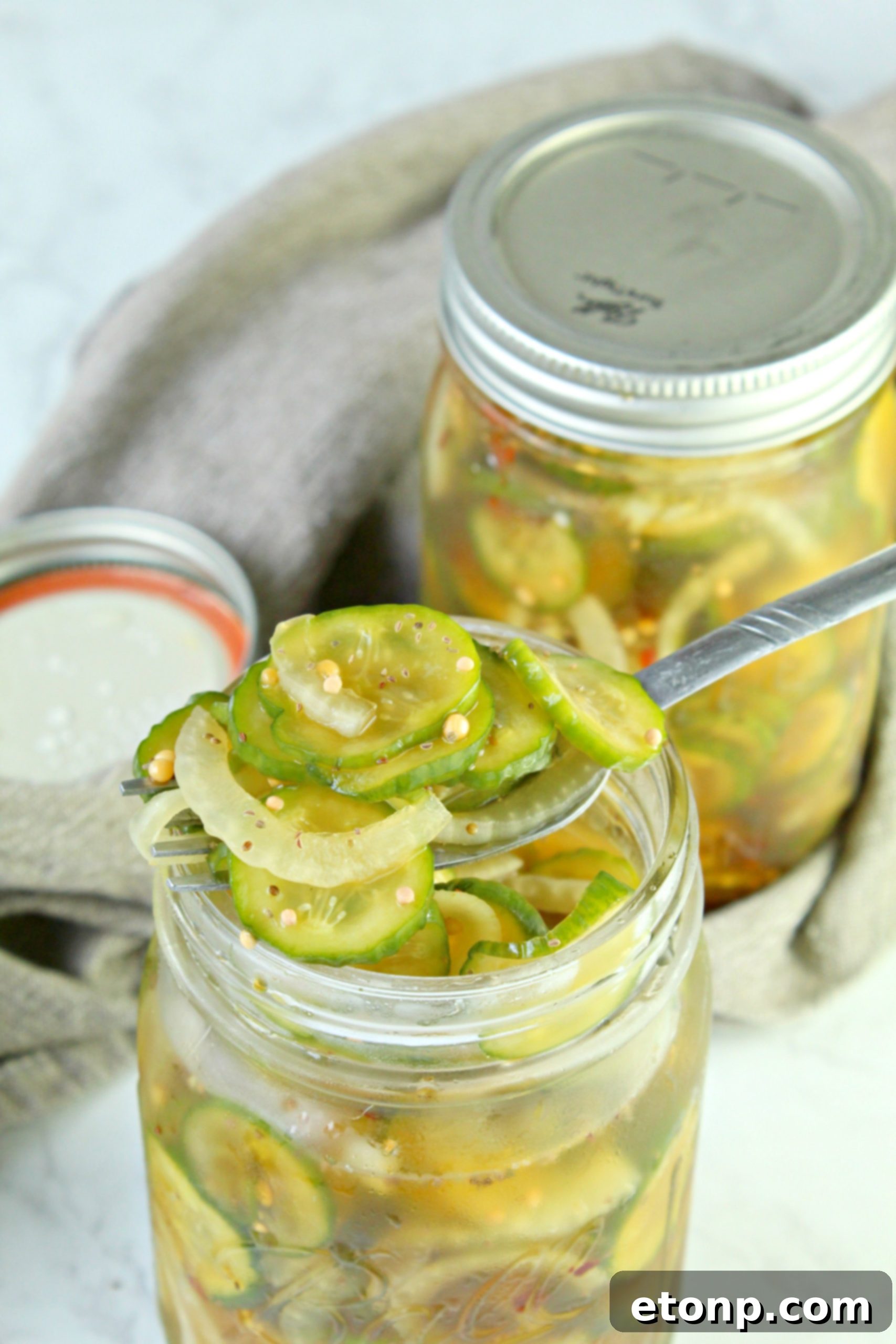 Multiple jars of homemade bread and butter pickles, some labeled and ready for long-term freezer storage, emphasizing preservation.