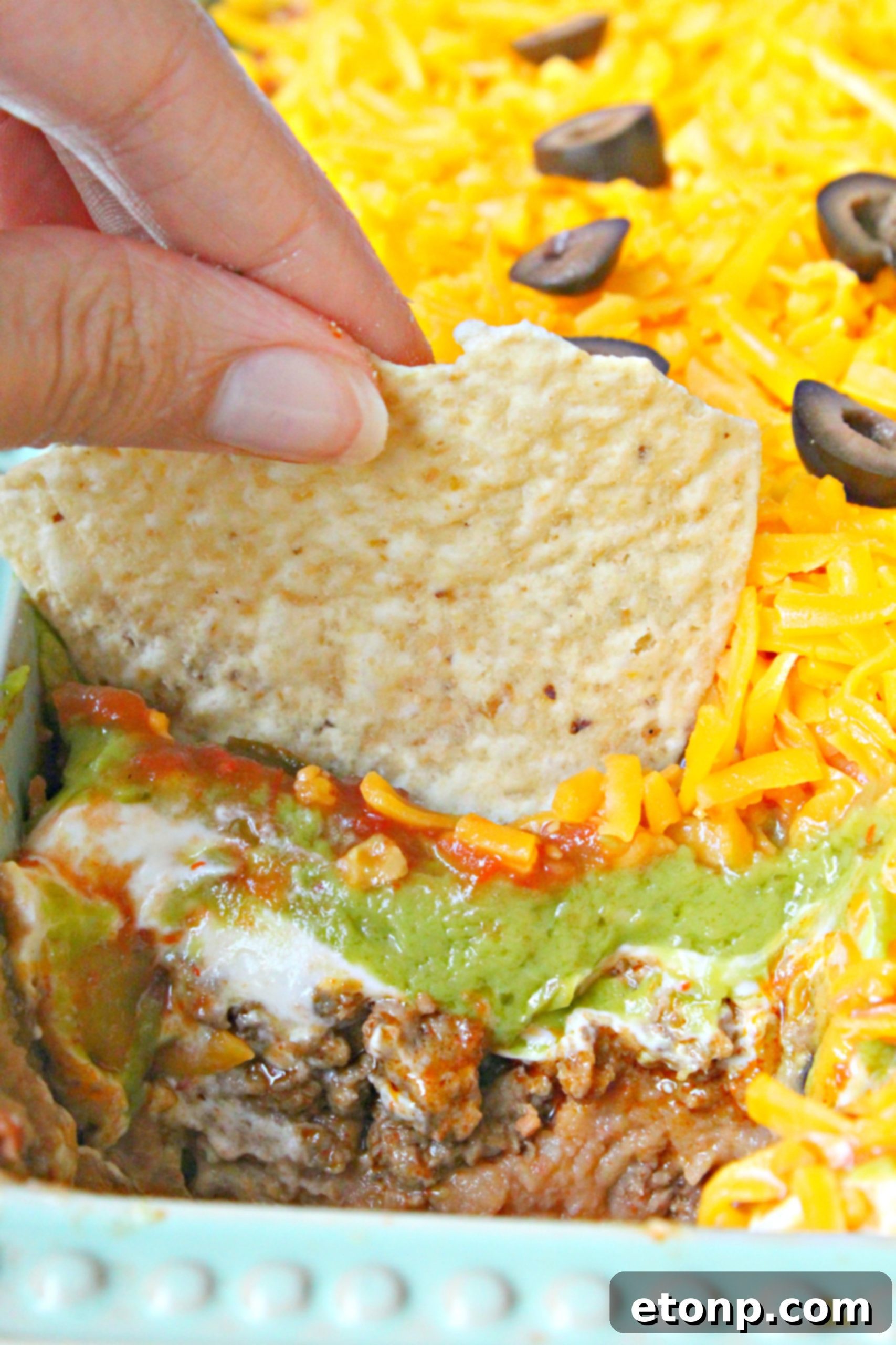 7 layer taco dip with a tortilla chip being dipped in