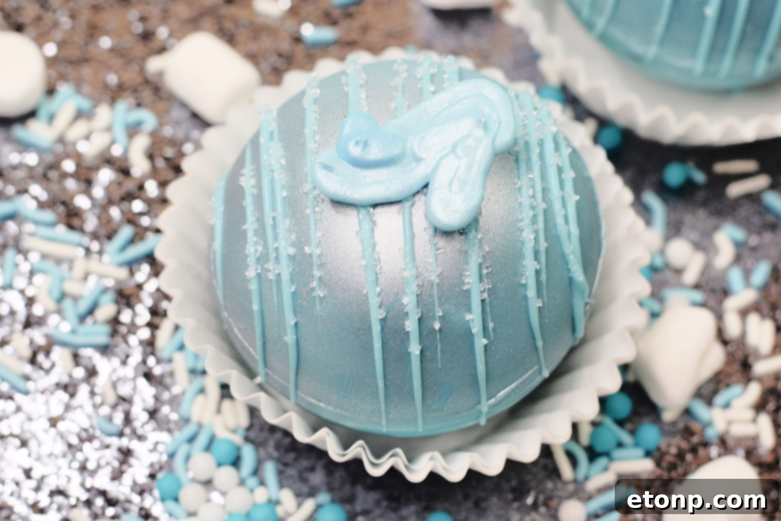 A beautifully crafted Cinderella Hot Cocoa Bomb, featuring a delicate blue chocolate shell and silver dust, ready to transform into a magical hot chocolate experience.