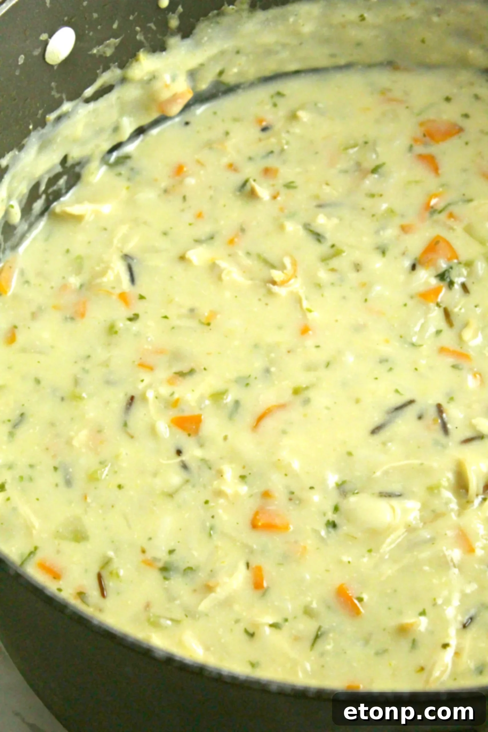 A clear plastic container filled with homemade Chicken & Wild Rice Soup, stored for future enjoyment.