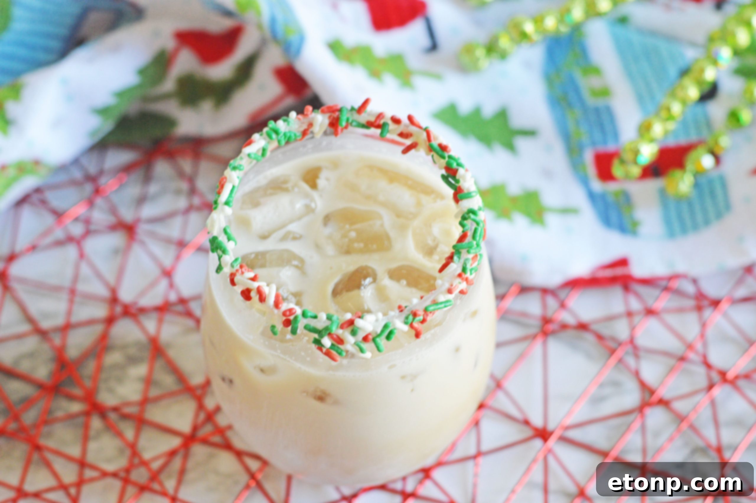 Hand holding a festive Christmas Cookie Cocktail with sprinkles.